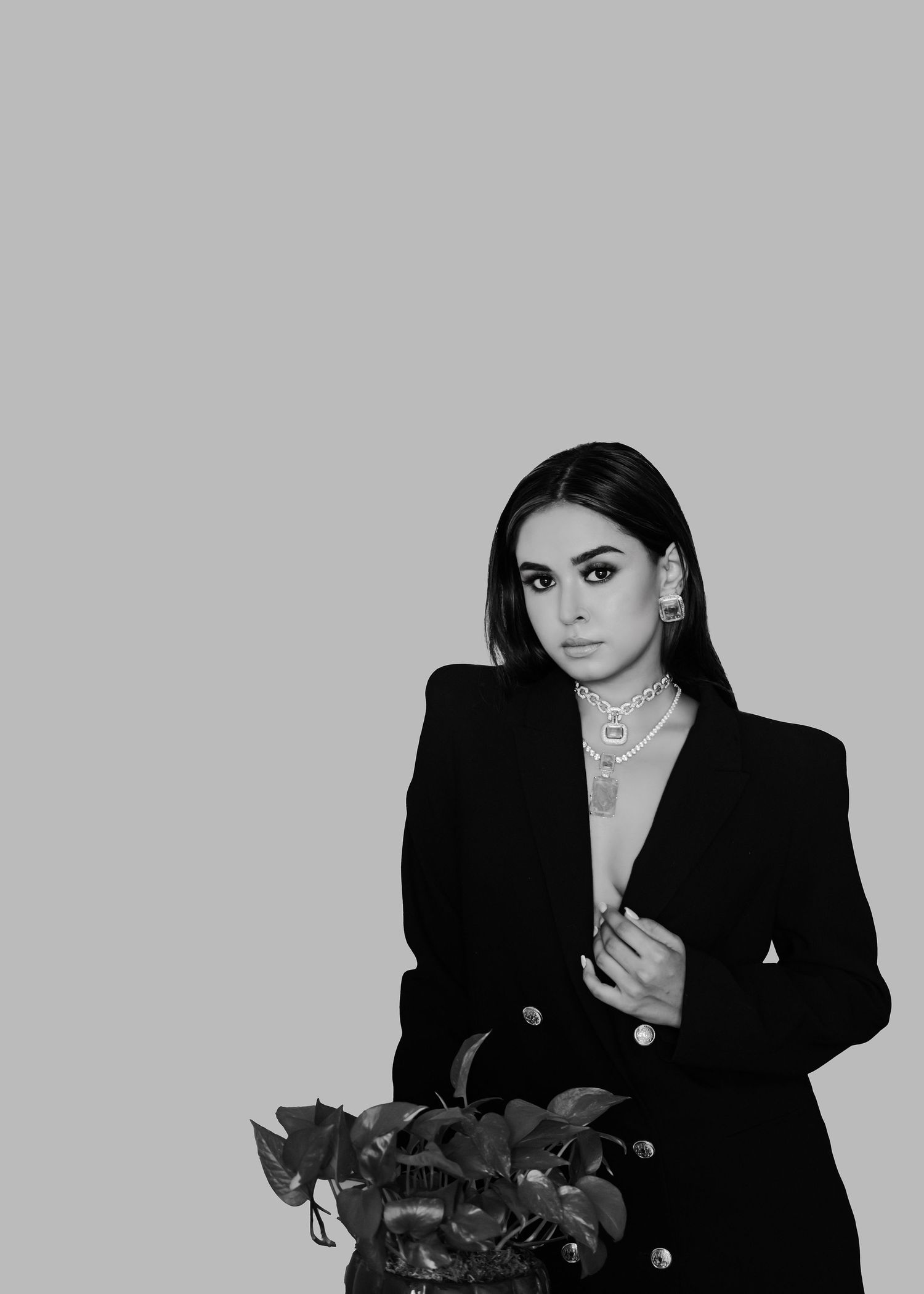 A stylish figure in a black blazer poses against a gray backdrop in a four-panel photo collage.