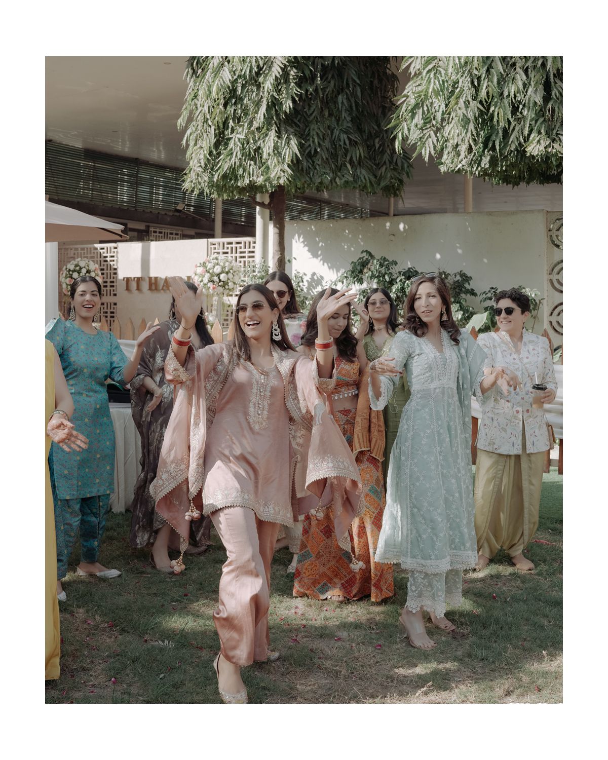 Wedding guests in pastel traditional attire celebrating outdoors.