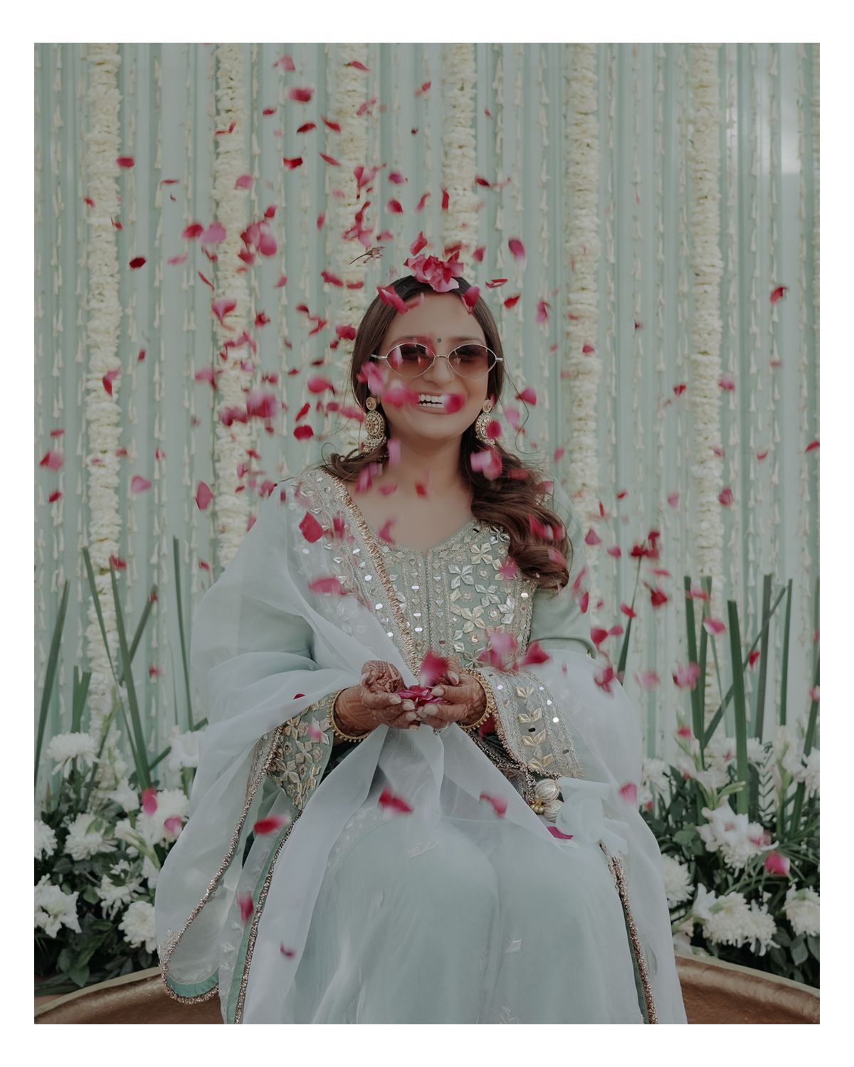 Joyful moment captured with rose petals falling against an elegant white floral backdrop.