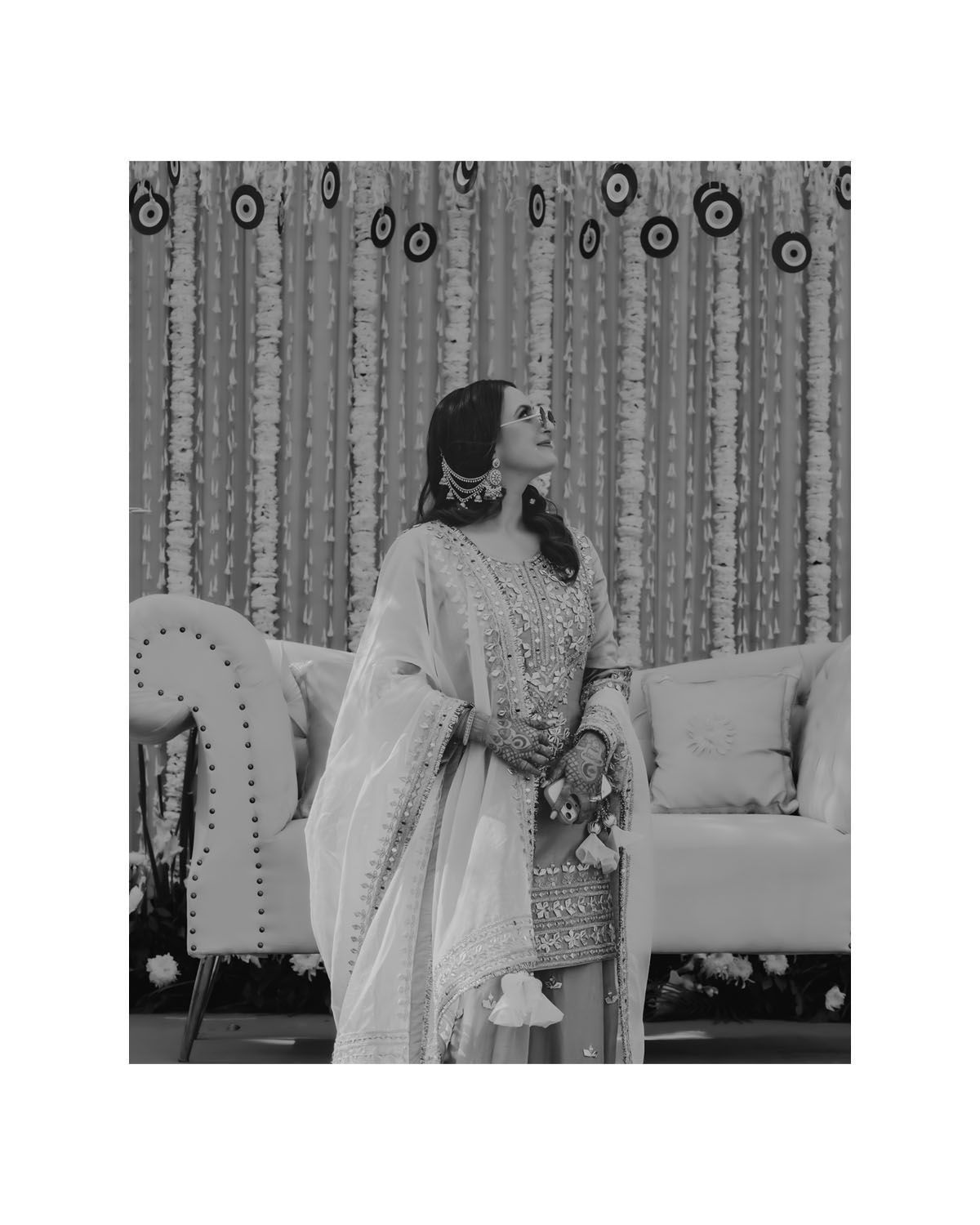 Black and white photo of someone in traditional dress posing against a decorated backdrop.