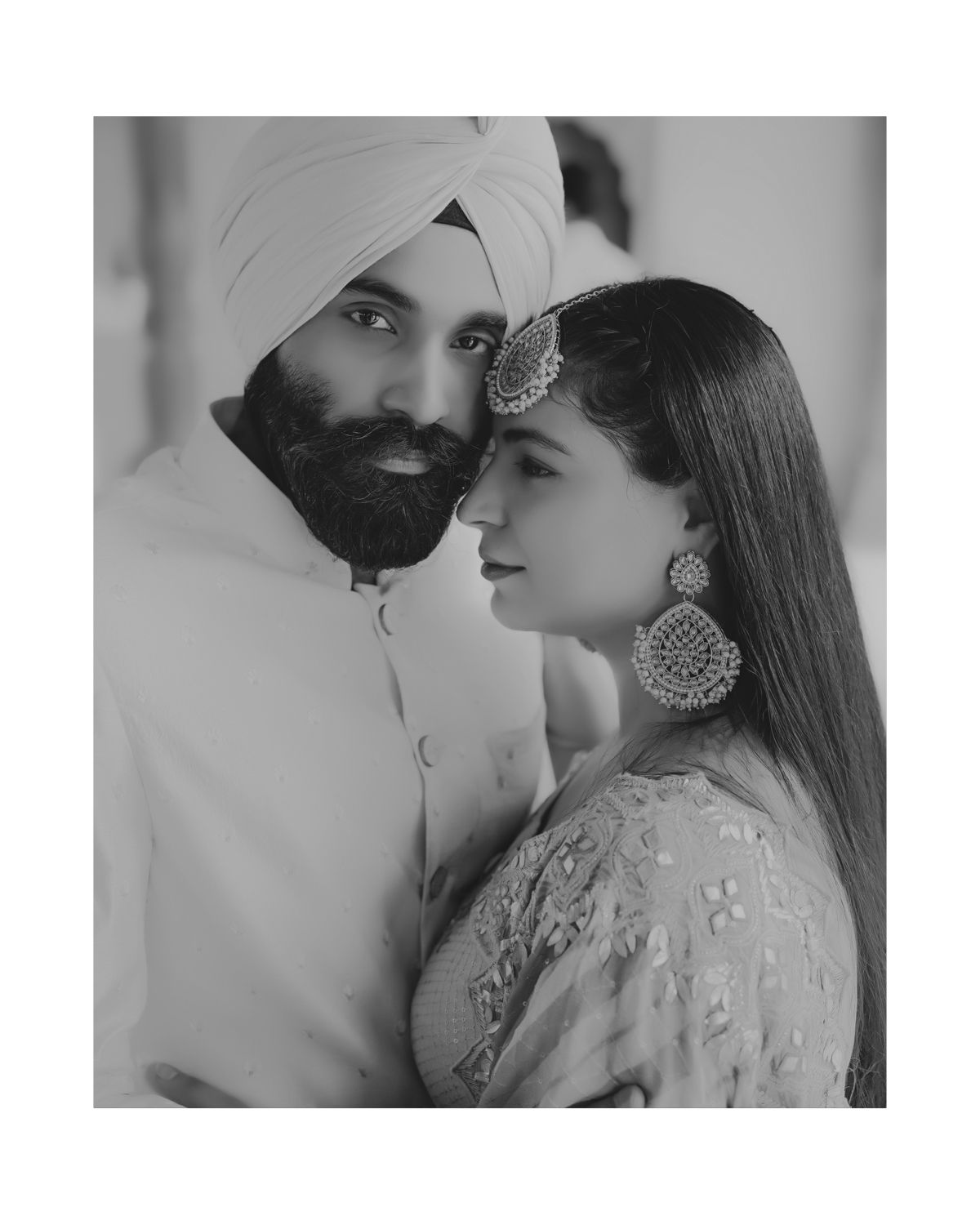 Traditional Sikh wedding portrait in black and white featuring ornate jewelry and attire.