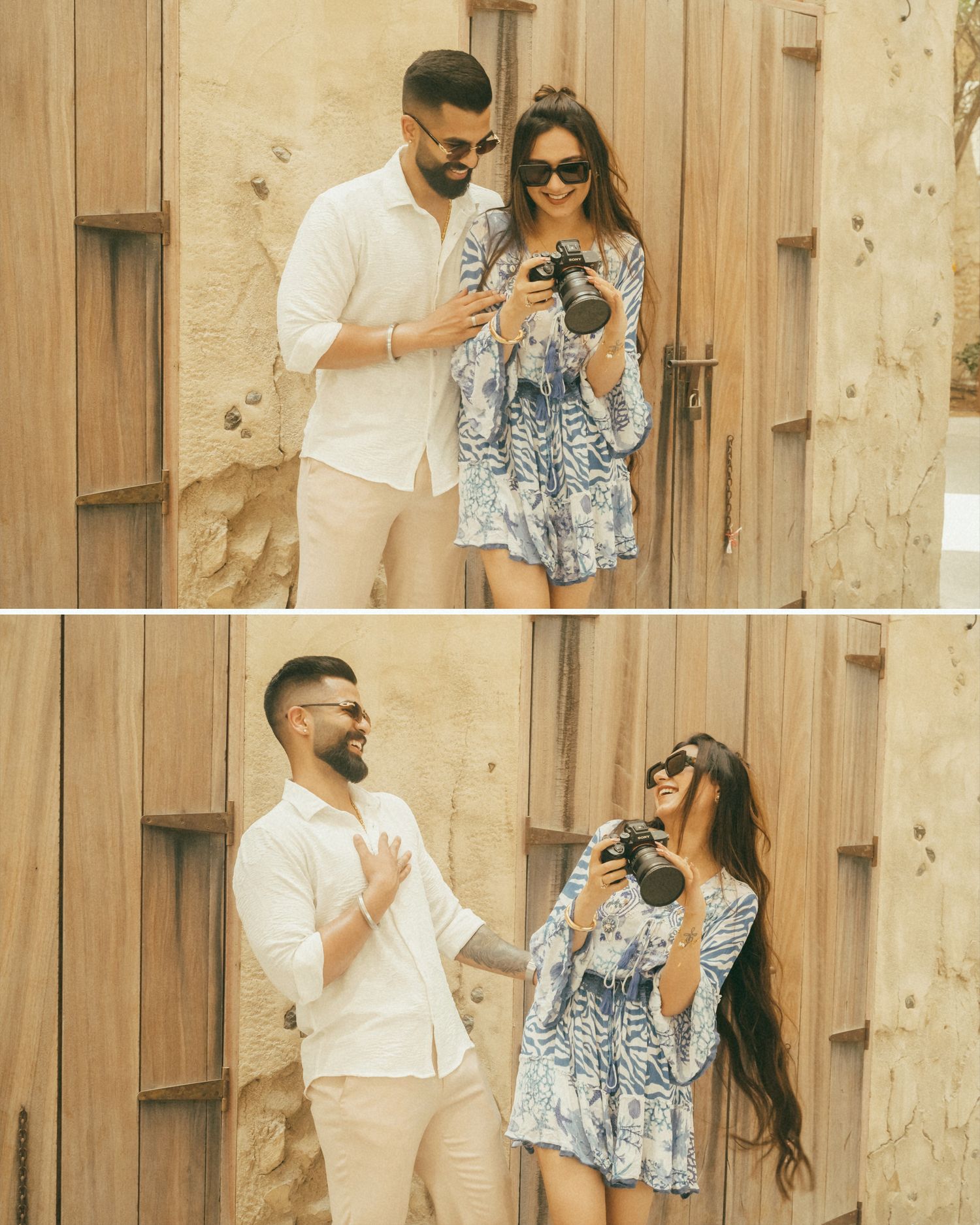 A couple shares a joyful moment reviewing photos on a camera near a wooden wall, the woman in a blue floral dress.