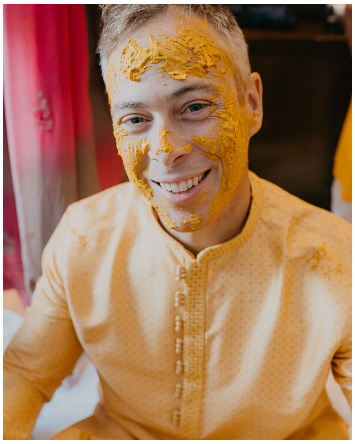 Close-up portrait during Haldi ceremony with yellow turmeric paste on face.