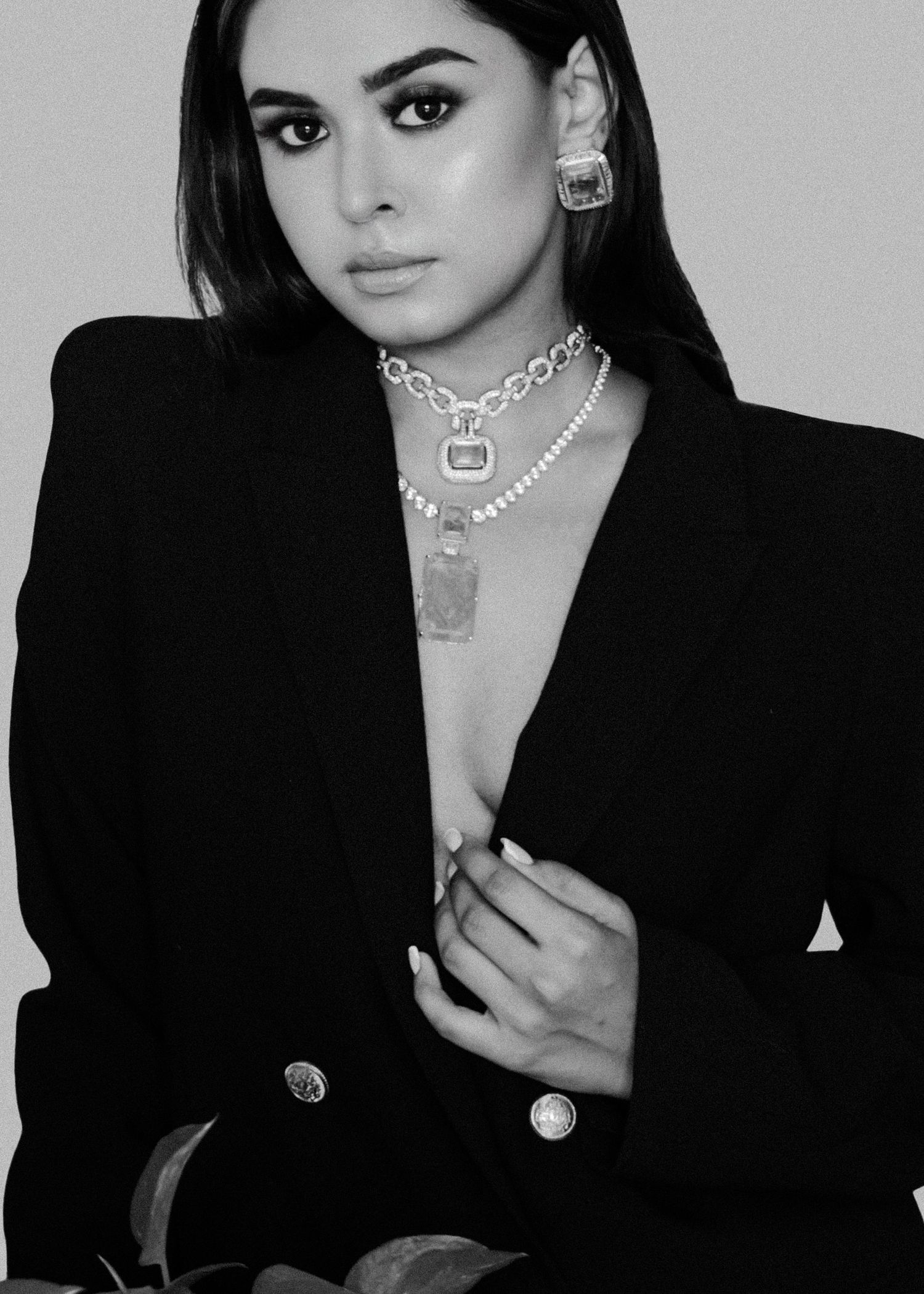 Black and white photo series showing someone wearing a black blazer and various silver necklaces posing in different angles.
