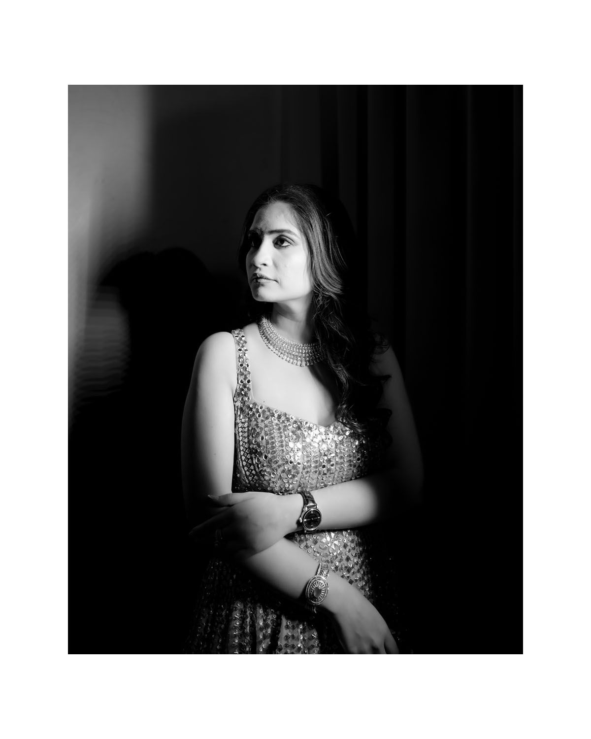 Dramatic black and white portrait of a woman in sequined gown looking to the side in moody lighting.