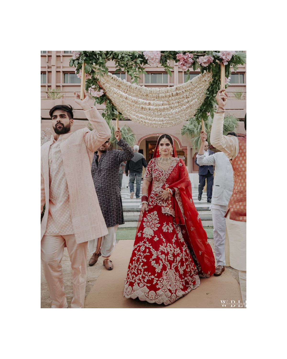 Elegant outdoor wedding ceremony with floral decorations and guests in traditional Indian formal wear.