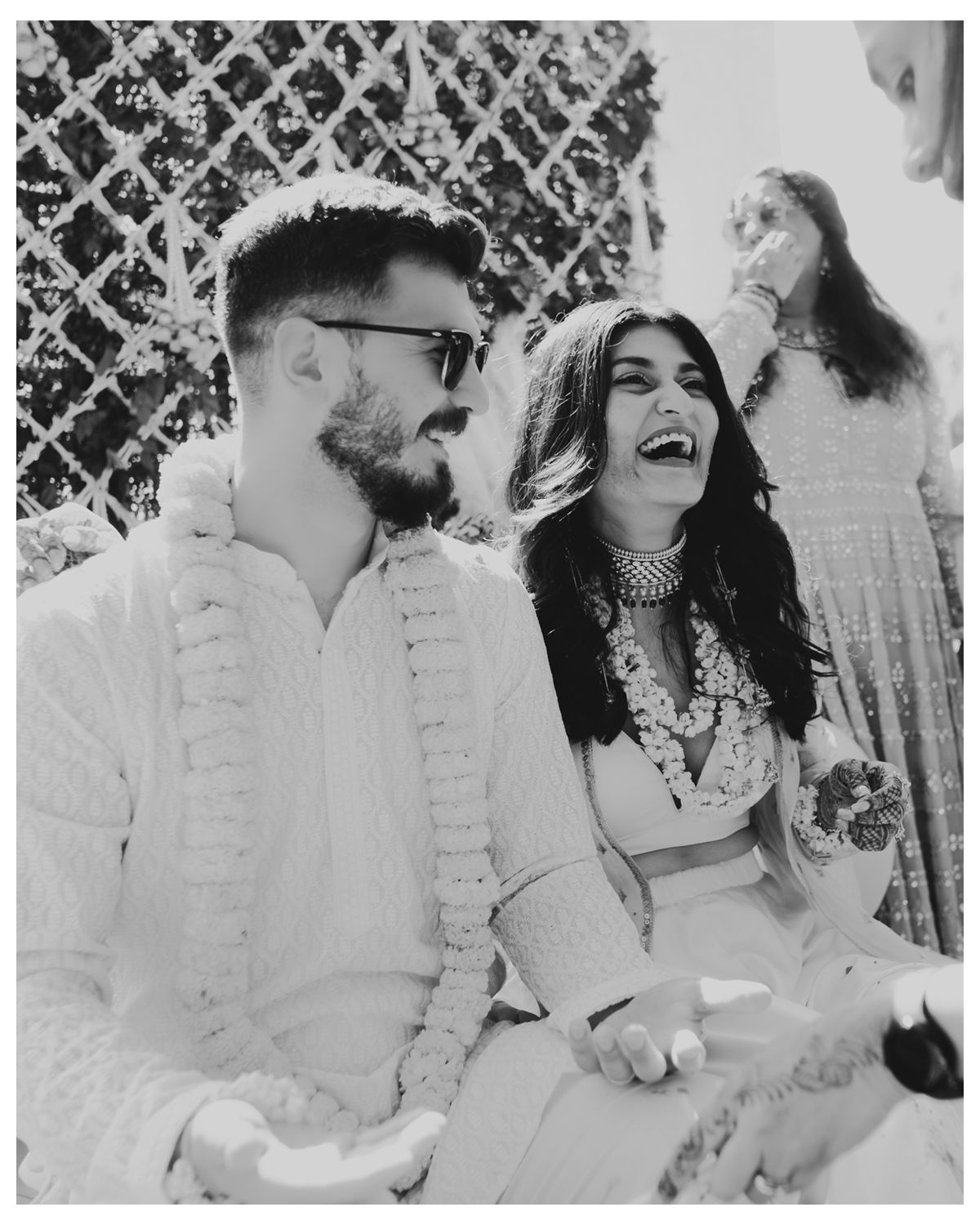 Black and white photo capturing a candid laughing moment at an outdoor celebration.
