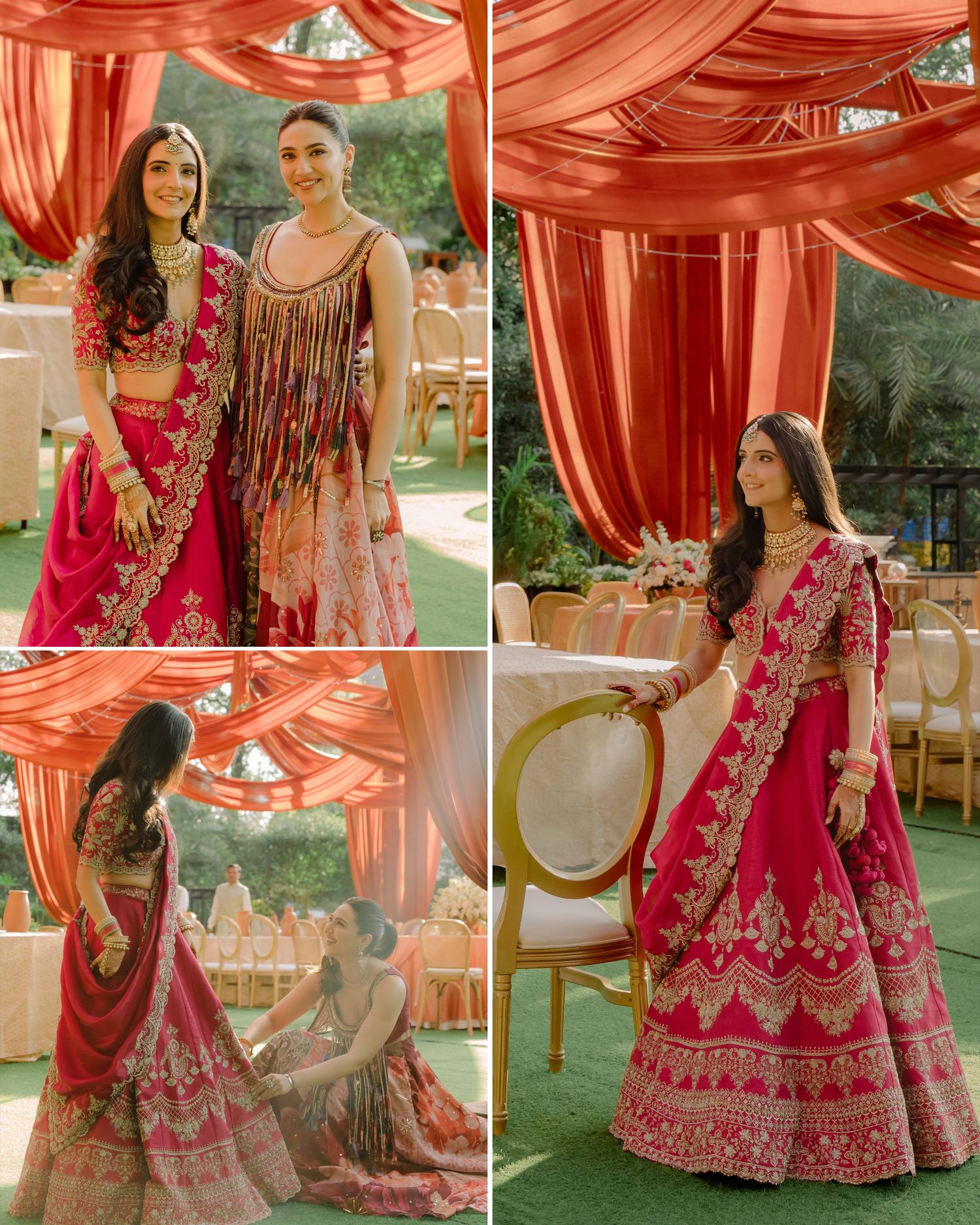 Two women in vibrant pink embroidered lehengas pose at an elegant Indian wedding venue with orange draping.