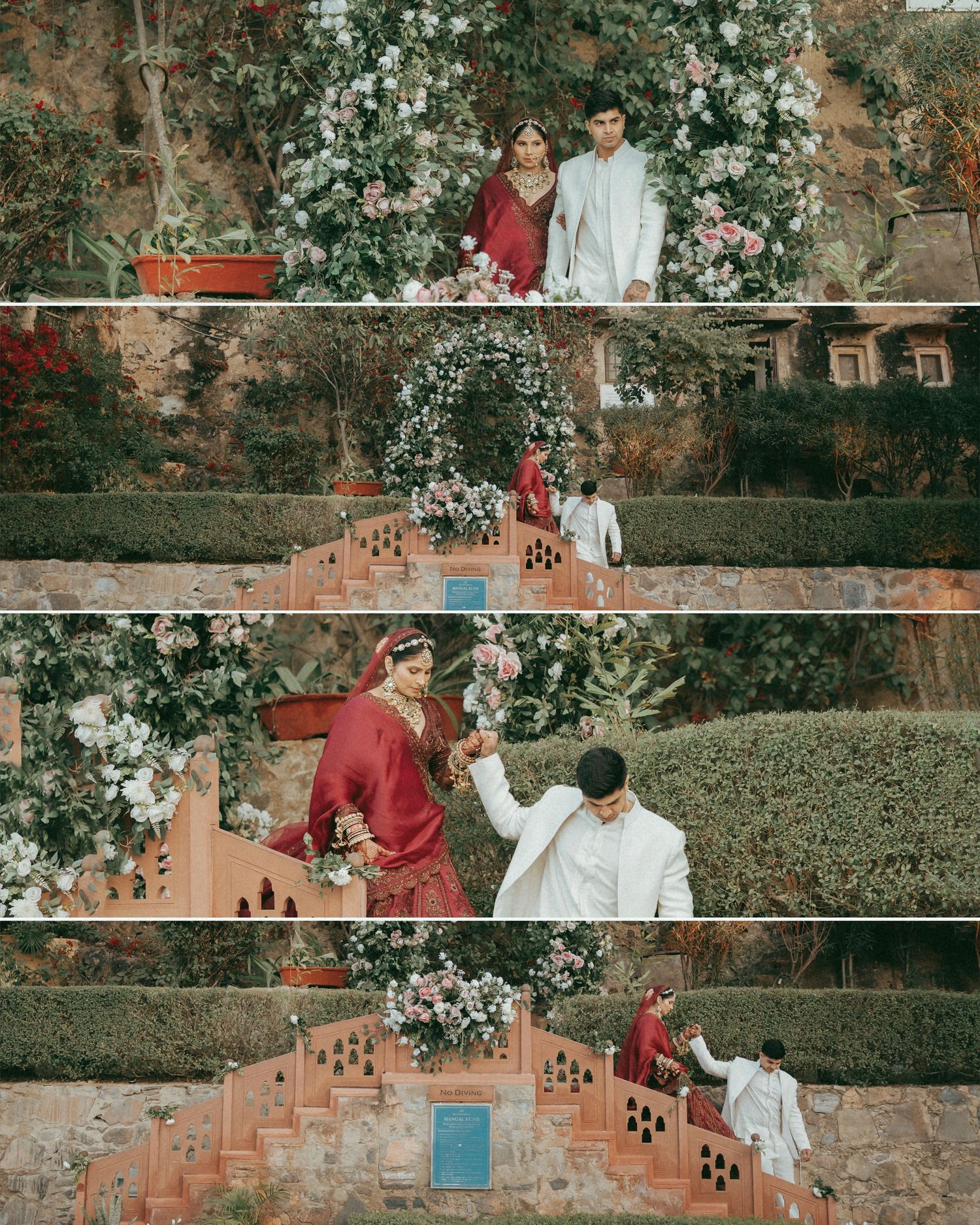 Indian couple in traditional wedding attire posing in a garden with floral arch, bride in red lehenga and groom in white sherwani.