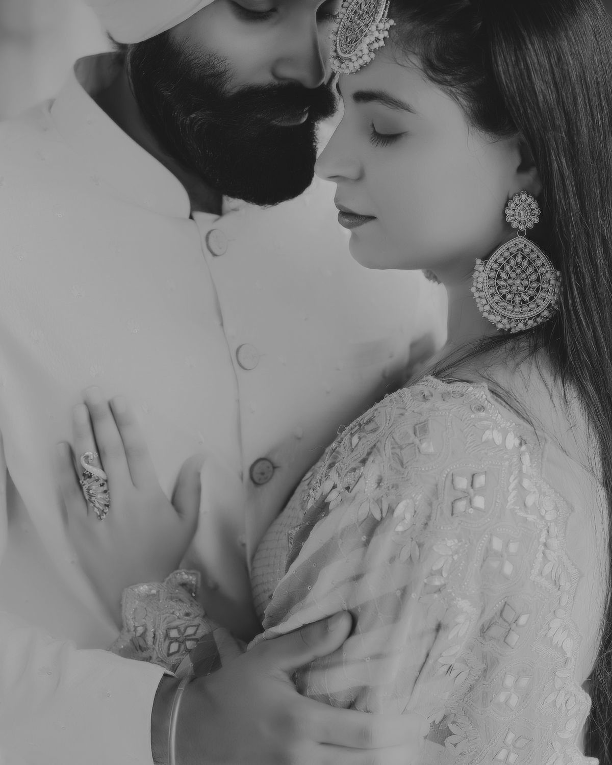 Intimate black and white portrait showcasing traditional Indian wedding attire and jewelry.