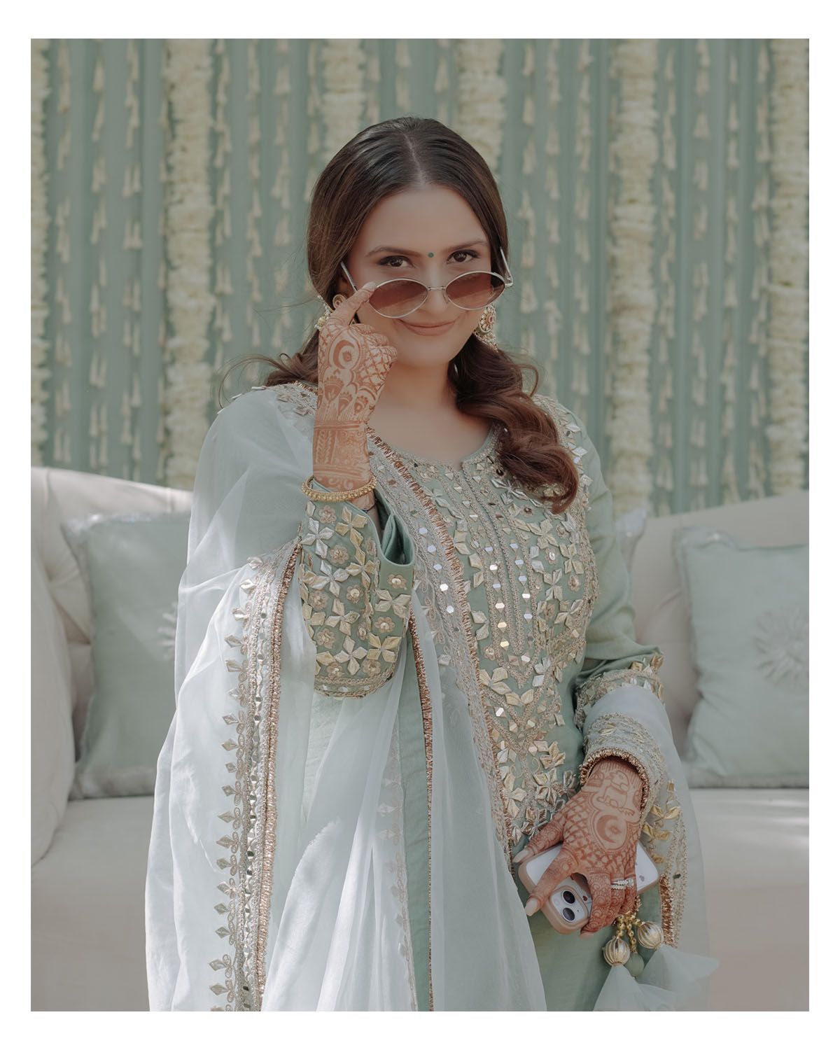 Elegant portrait of a bride in embellished white outfit with henna designs.