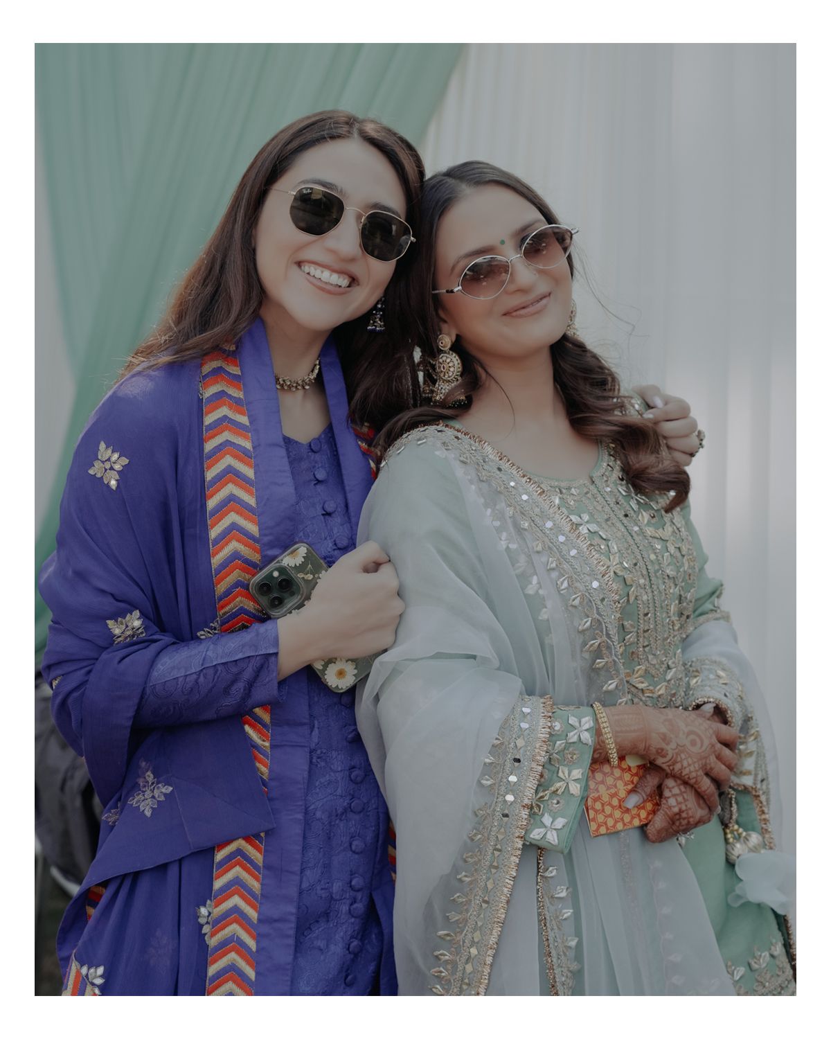 Two friends in traditional Indian attire pose together at a festive event.