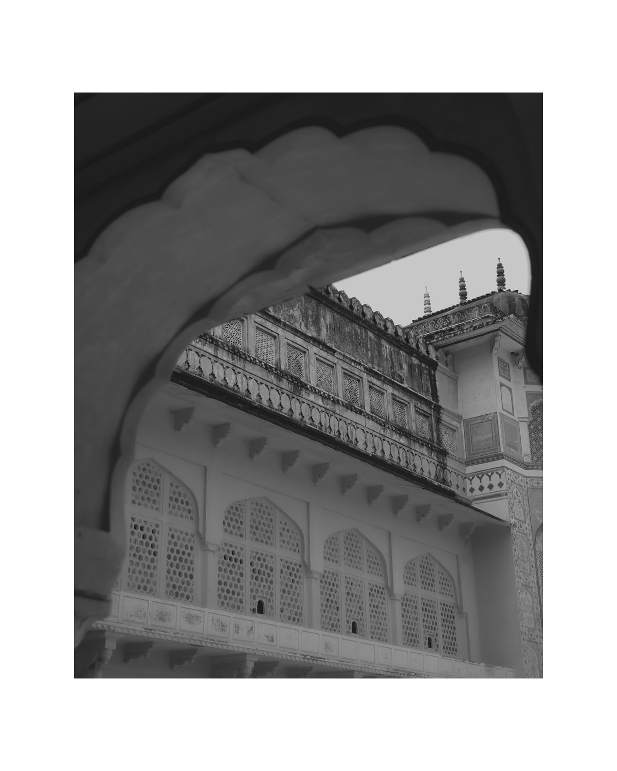 Elegant archways and latticed windows of an Indian palace captured through a curved architectural frame.