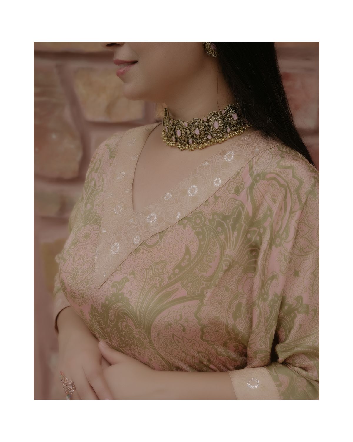 Close-up detail of an ornate golden choker necklace worn with a peach and gold embroidered outfit.