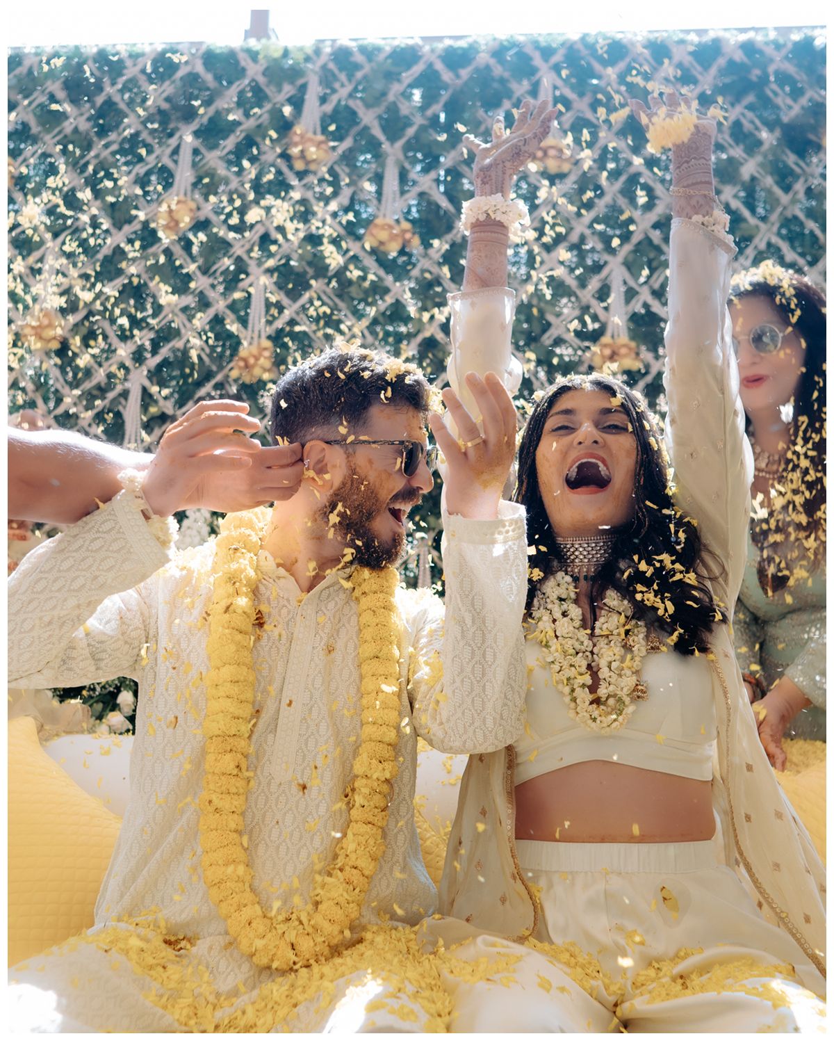 A joyous couple celebrates with raised arms during a traditional Indian wedding ceremony.