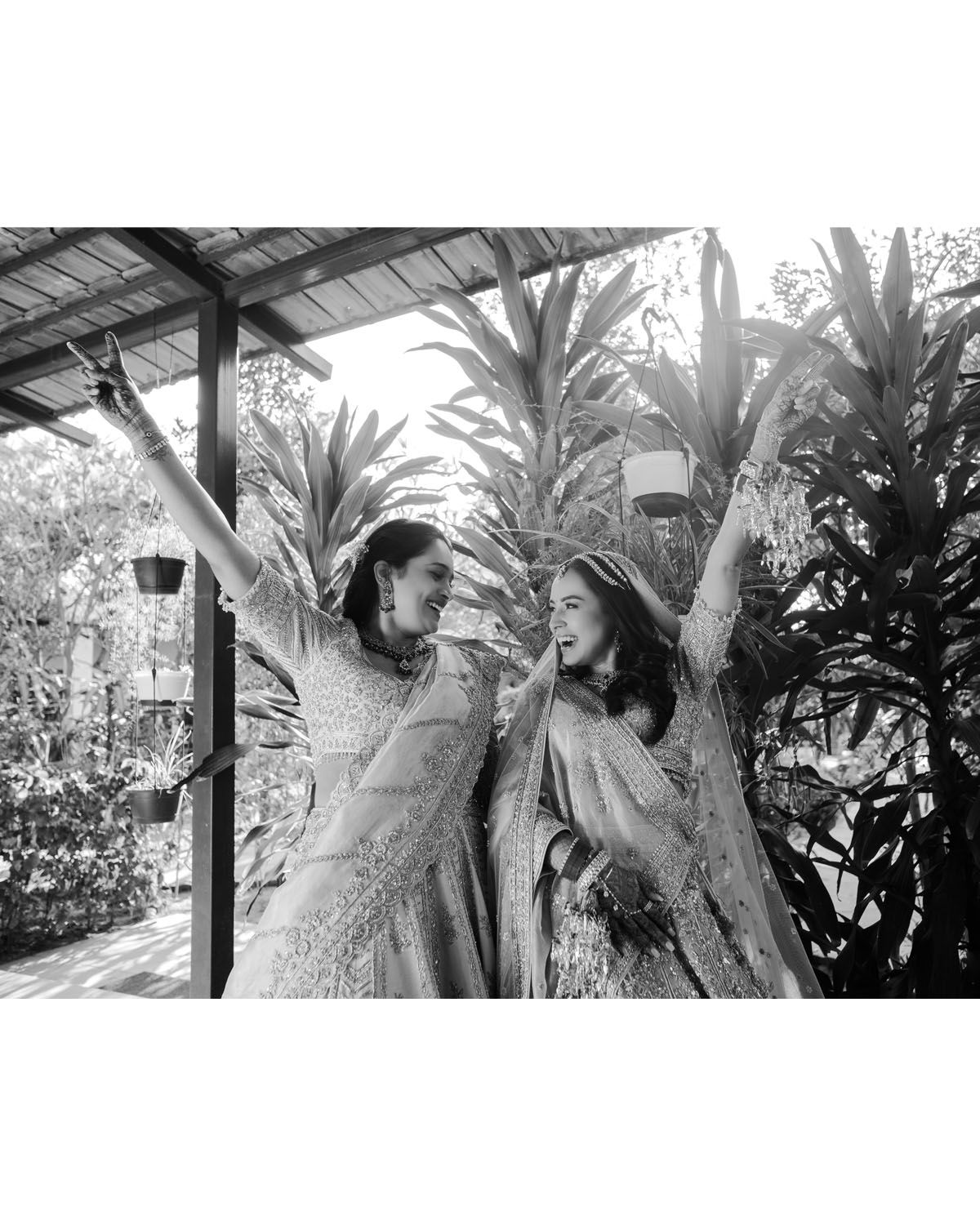 Two people in elegant outfits share a joyful moment together in a black and white photograph.
