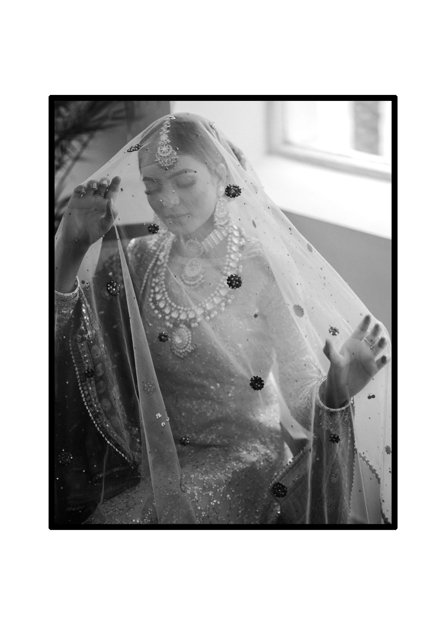Traditional South Asian bridal portrait in black and white showing intricate jewelry and veil details.
