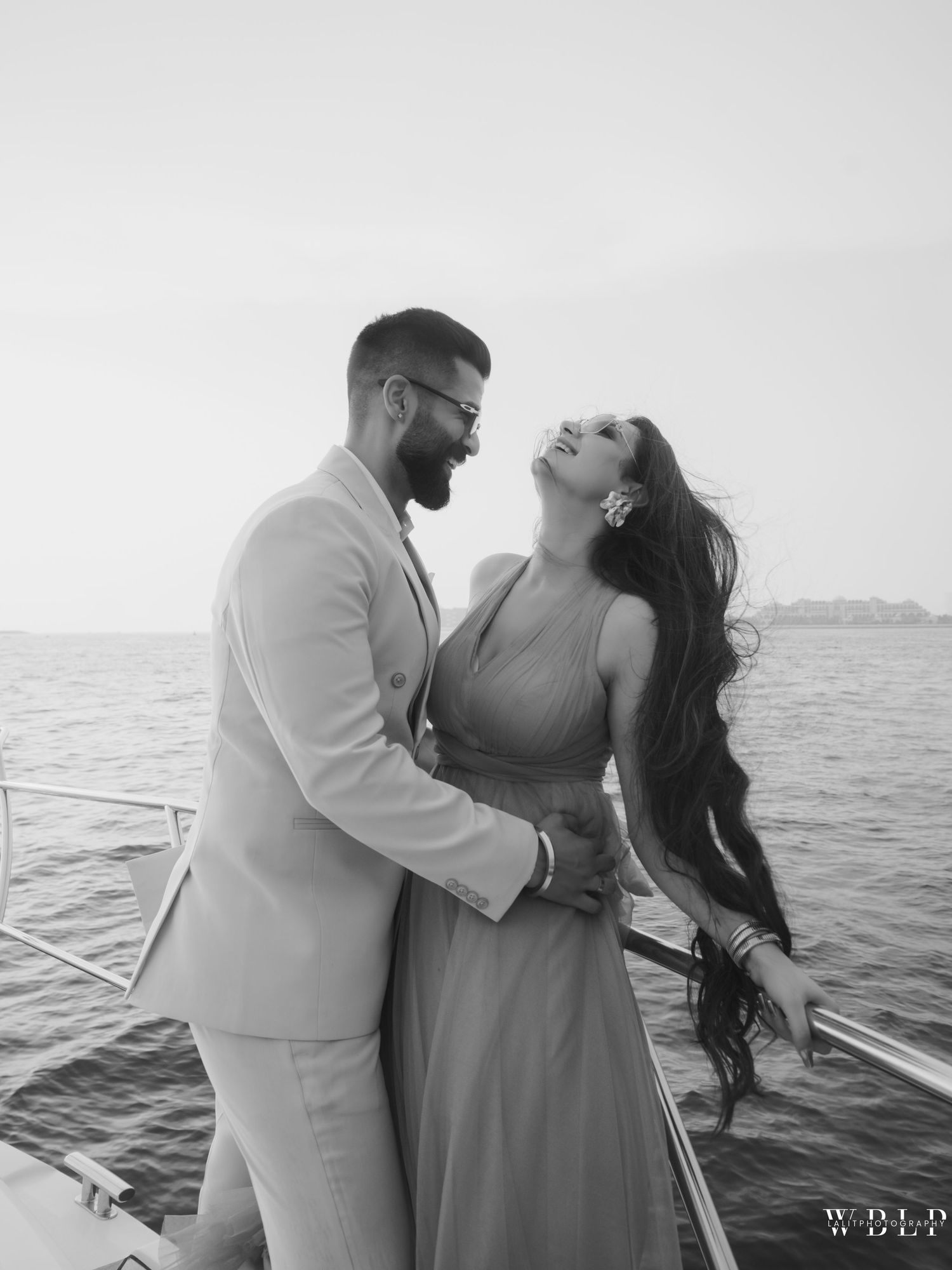 Couple sharing a romantic moment on a boat over the ocean, black and white engagement photo.