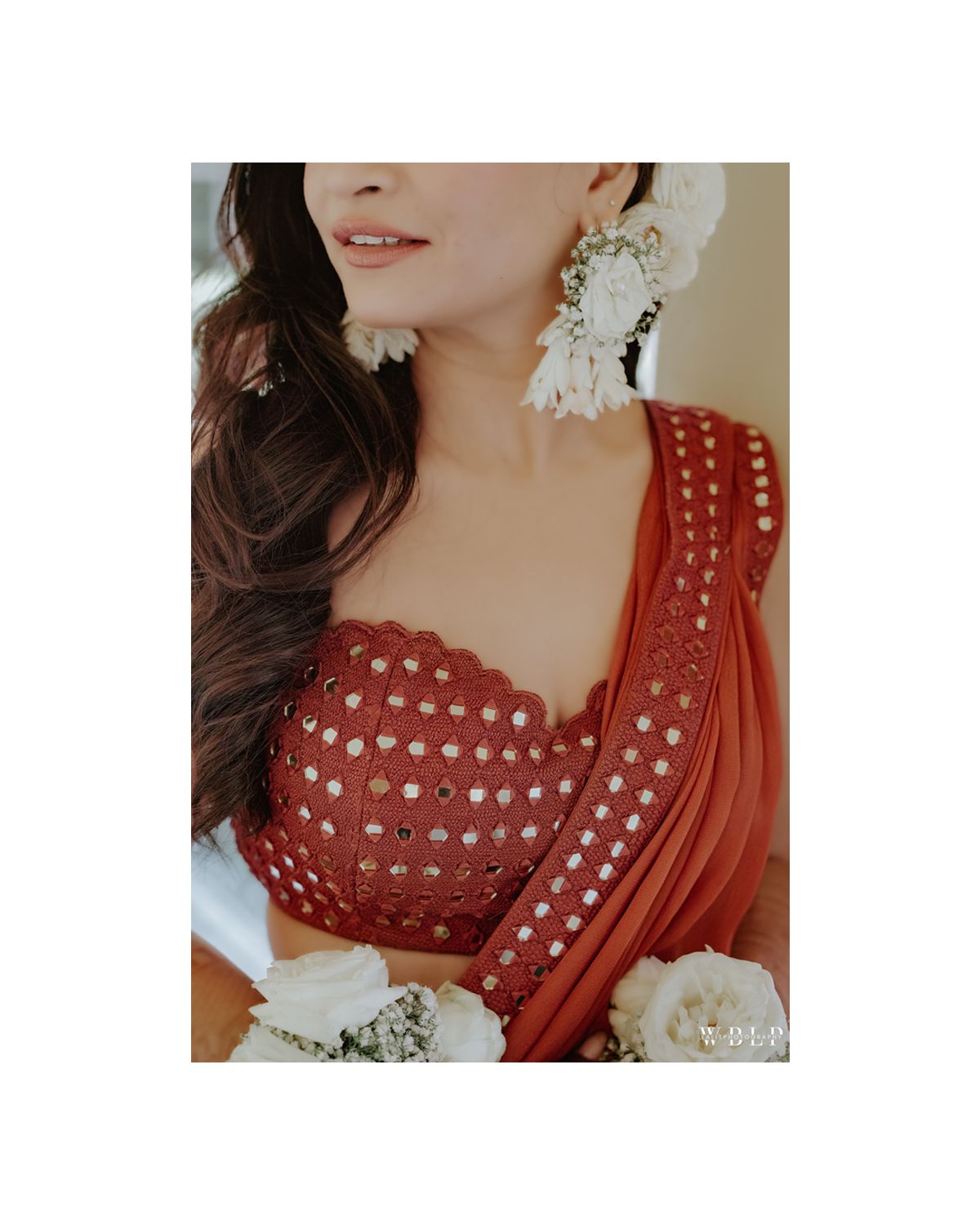 Close-up of red embroidered traditional dress with white floral accessories.
