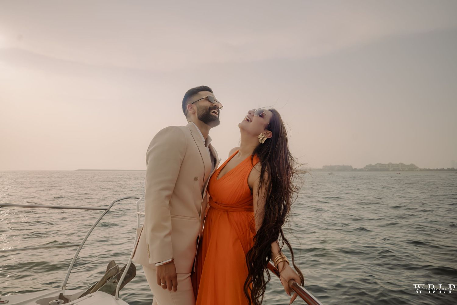 Couple in elegant attire sharing a romantic moment on a boat with ocean backdrop at sunset.
