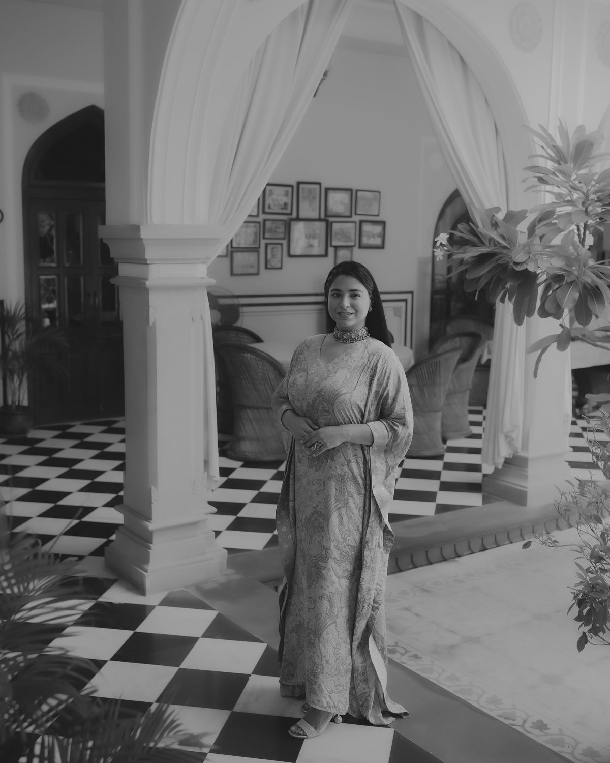 Black and white photograph of an elegant interior with arched columns and checkered flooring.
