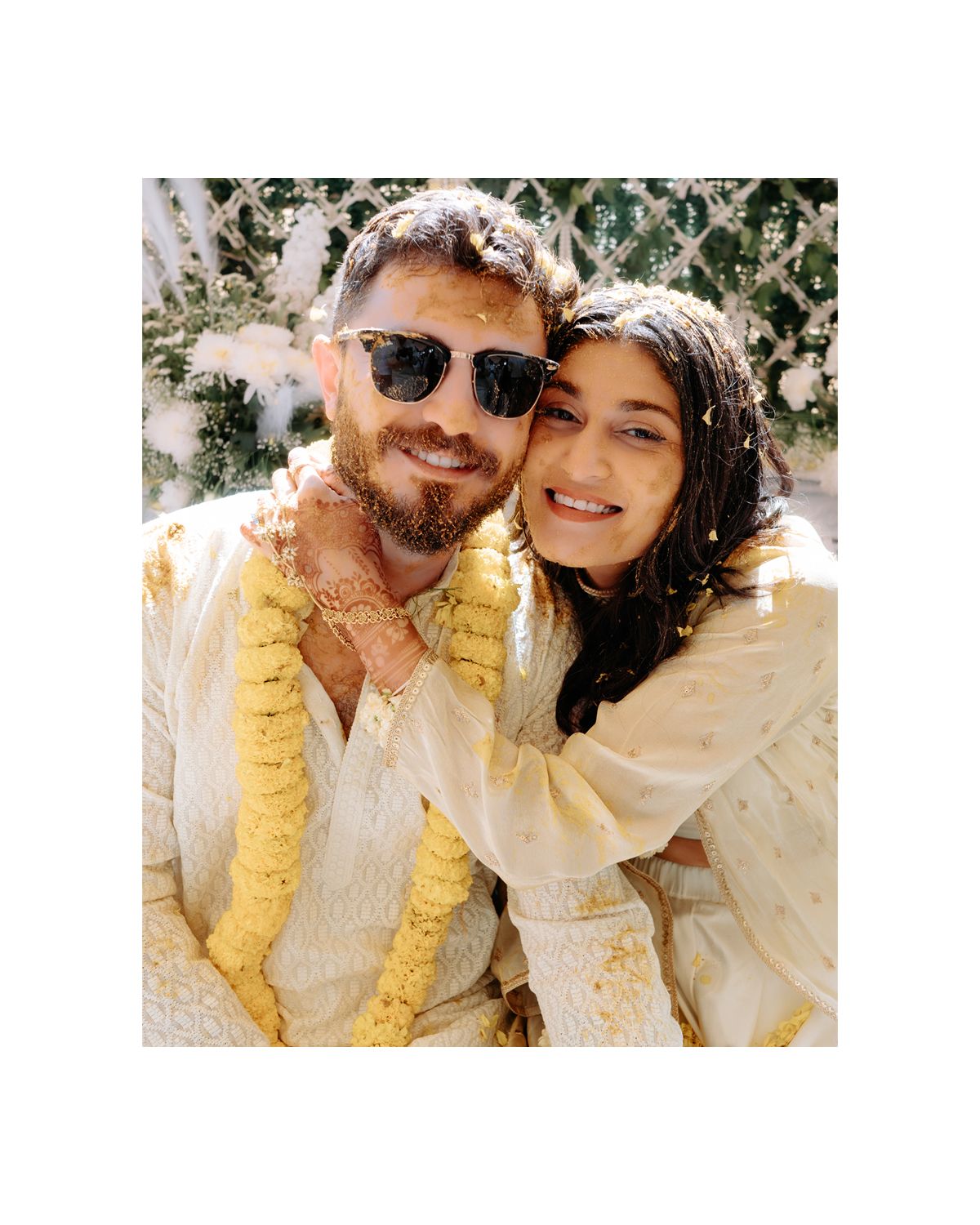 A couple in matching cream outfits smiles during their wedding celebration.