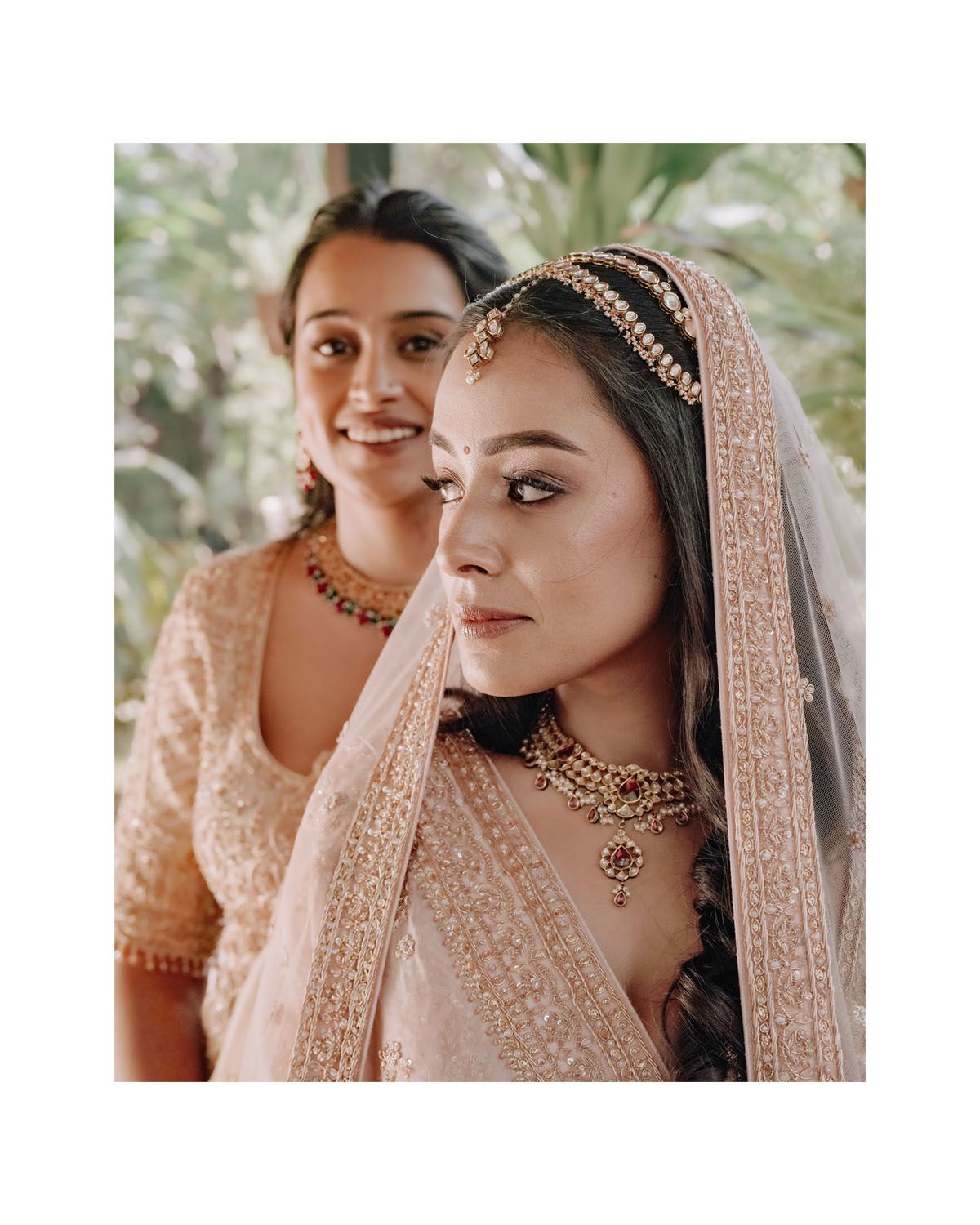 Traditional Indian bridal attire featuring intricate jewelry, delicate embroidered veil and elegant makeup details.
