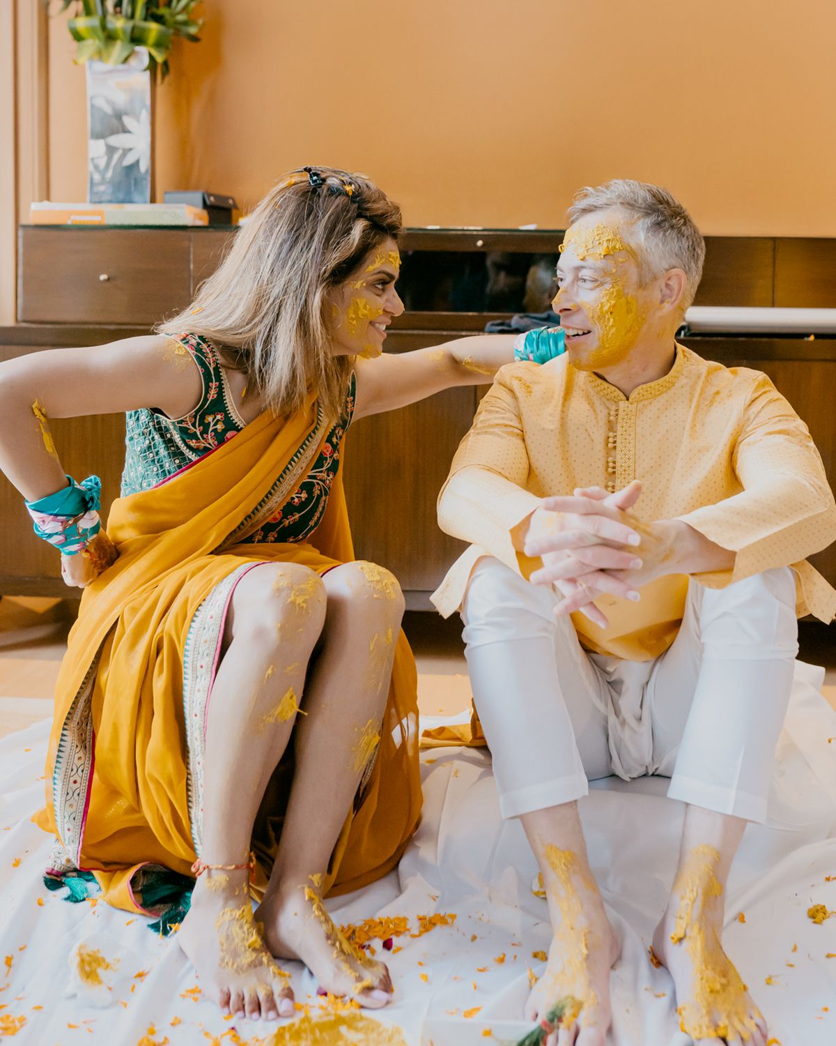 A festive Haldi ceremony moment with yellow turmeric powder and playful interactions between the couple.