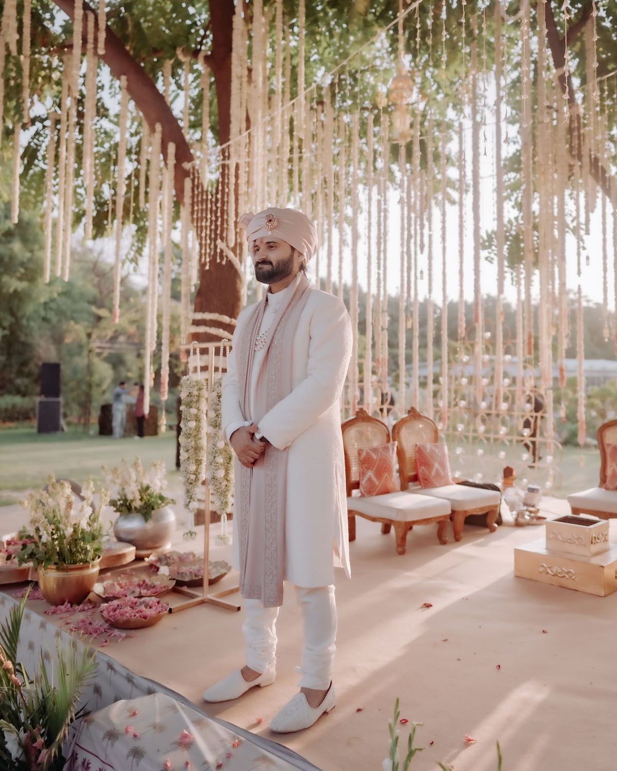 An outdoor wedding setup with hanging floral decor and elegant seating arrangements in a garden setting.