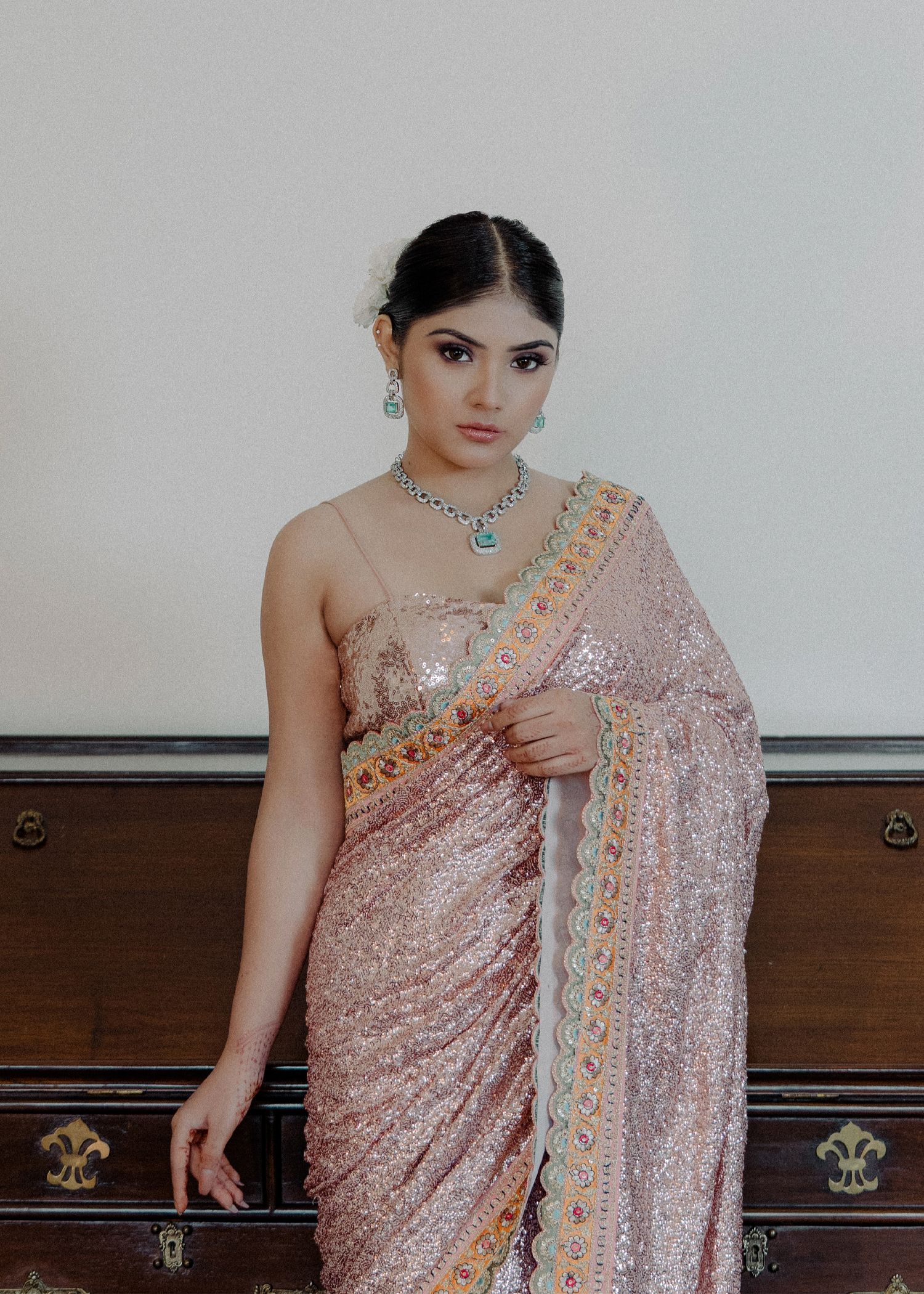 A collage of someone wearing a delicate pink sequined saree with intricate embellishments and statement jewelry.