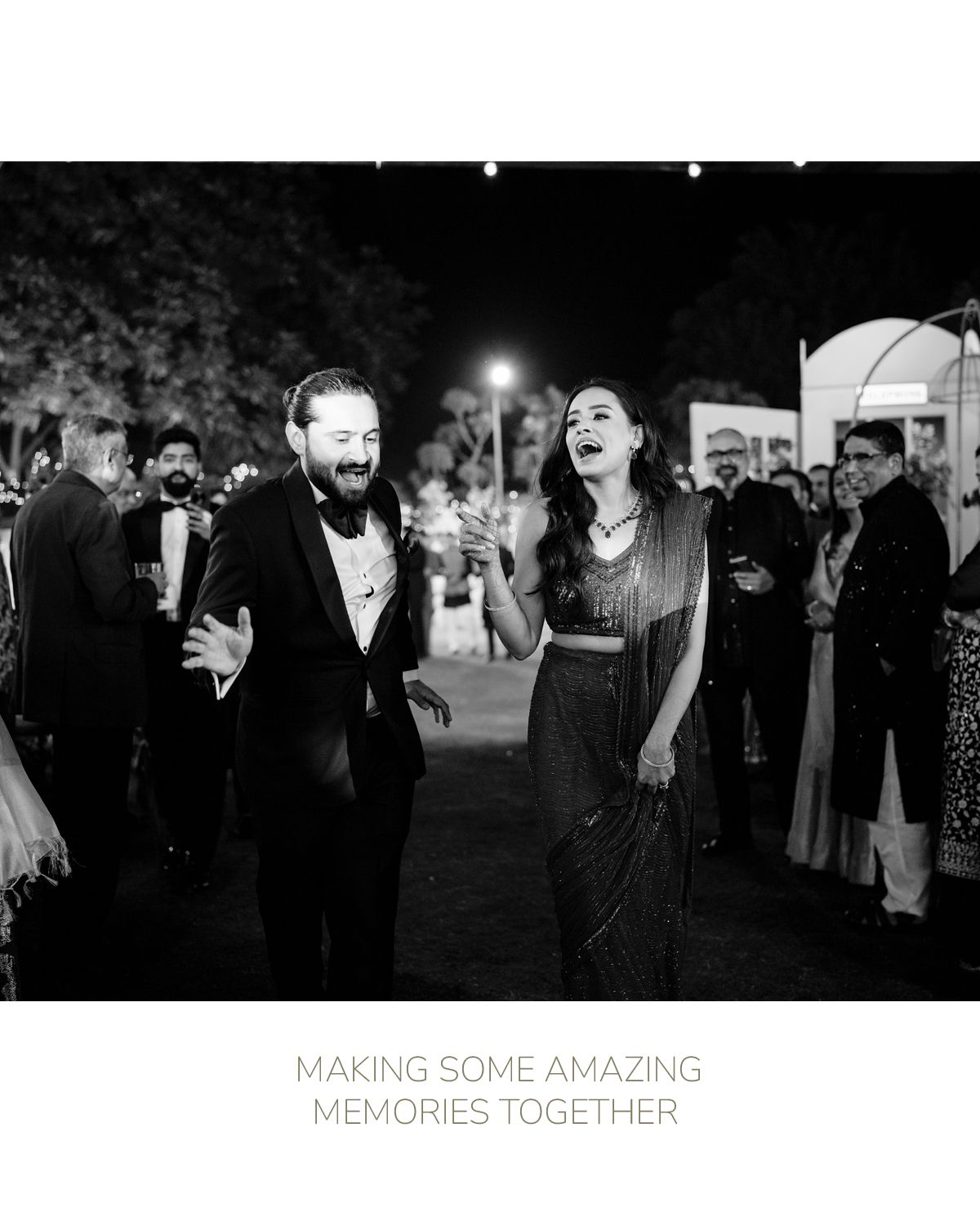 A joyful couple laughs together during a nighttime outdoor celebration in black and white photography.