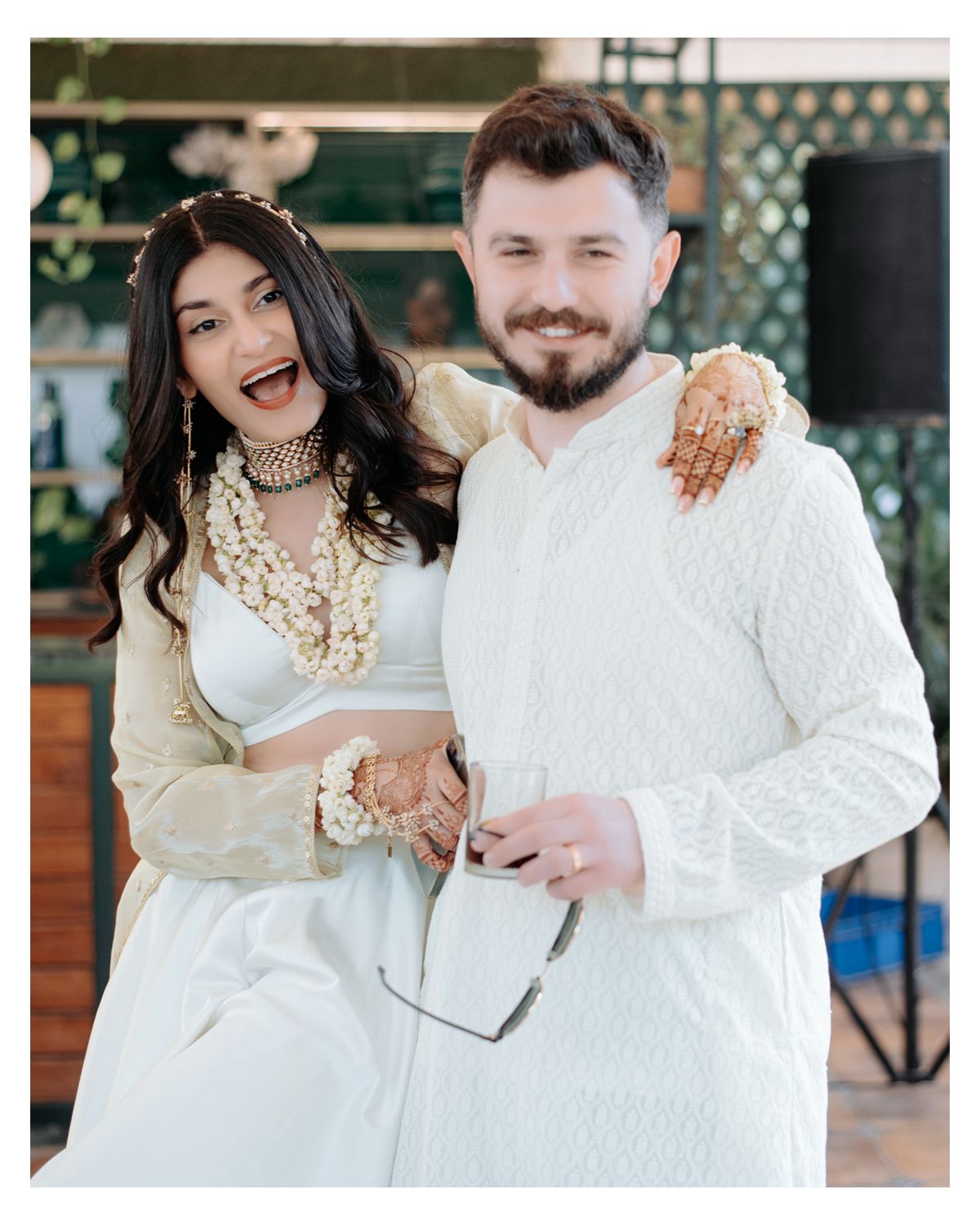 Joyful couple in coordinated white outfits share a candid moment during their celebration.