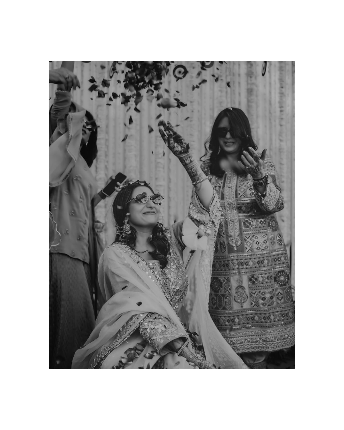 Black and white photo of bride and friend throwing petals during celebration.