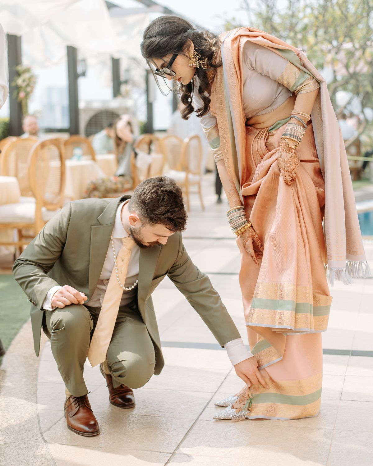 Wedding couple in traditional attire sharing a playful moment on patio.