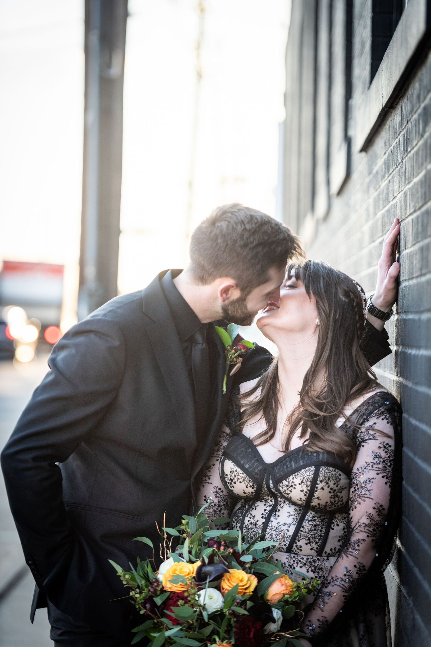Couple sharing intimate moments against an industrial wall with wedding bouquet. Whitney McLaren Photography