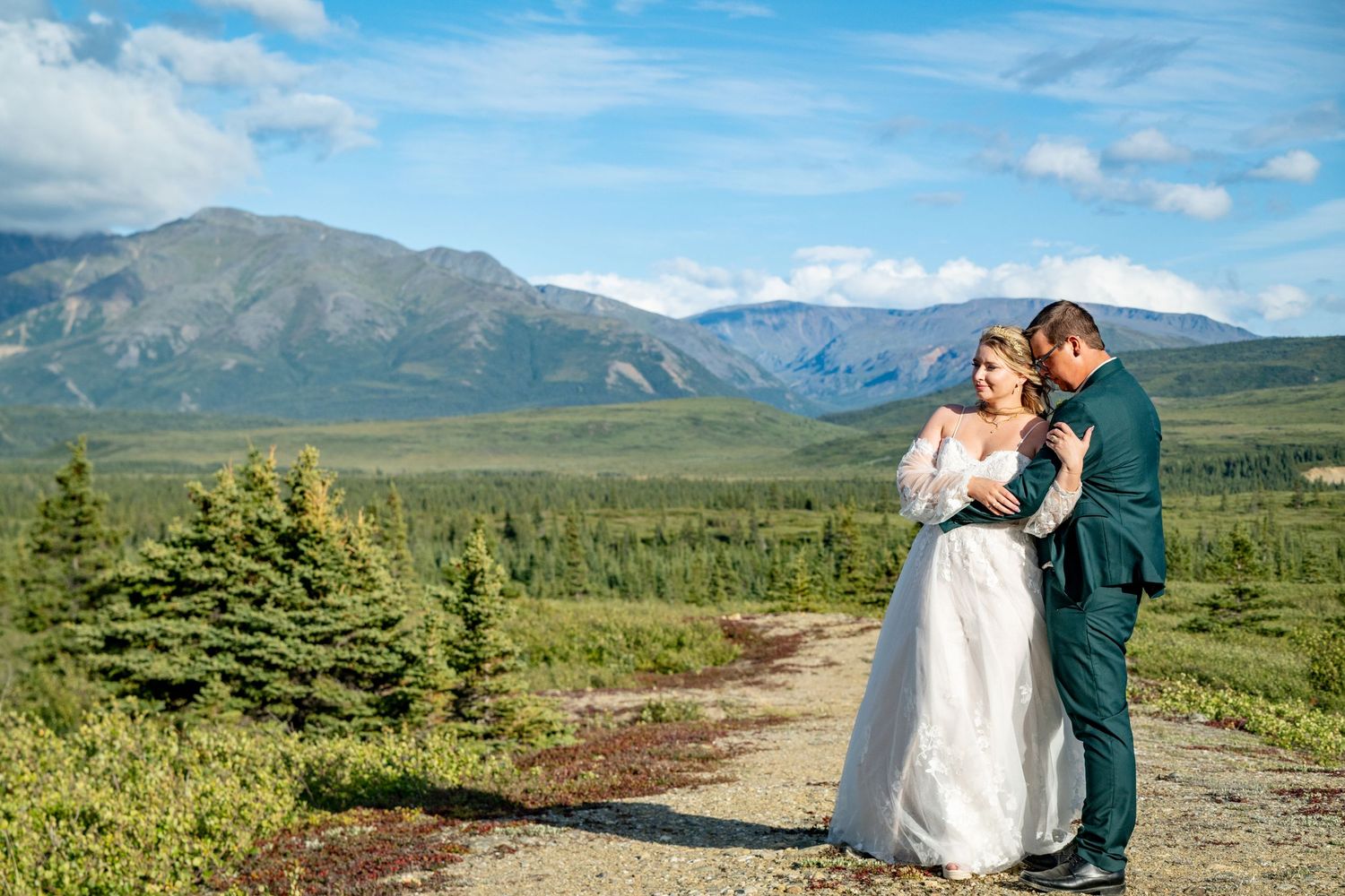 Wedding couple embracing on mountain path with scenic landscape views.  Whitney McLaren Photography