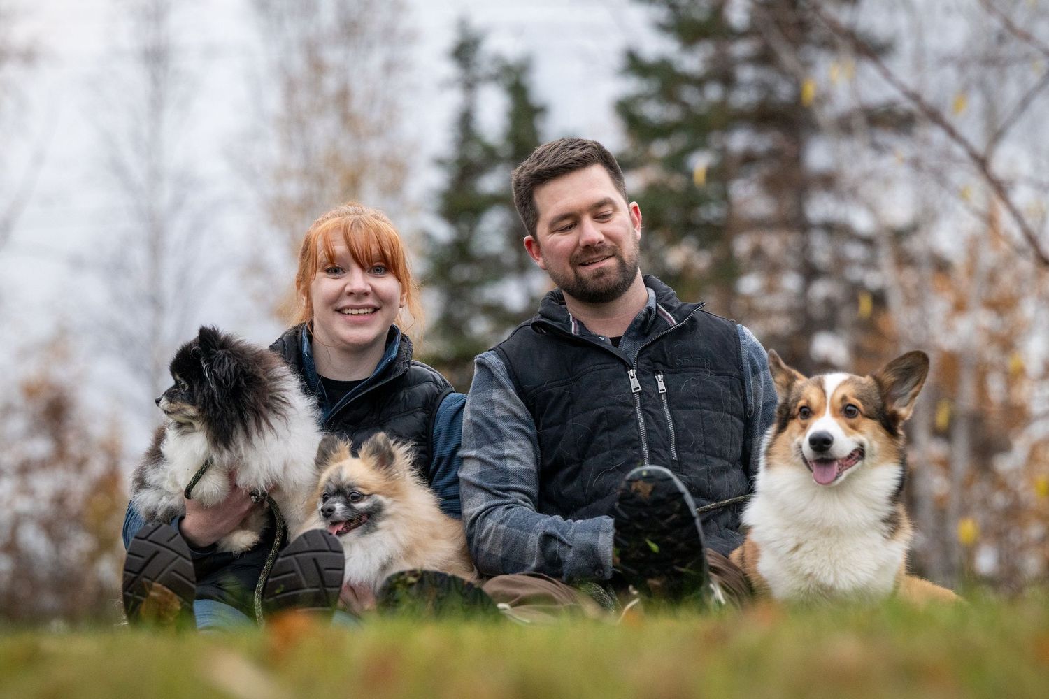 Group of people and dogs enjoying a playful moment together outdoors in an autumn setting.