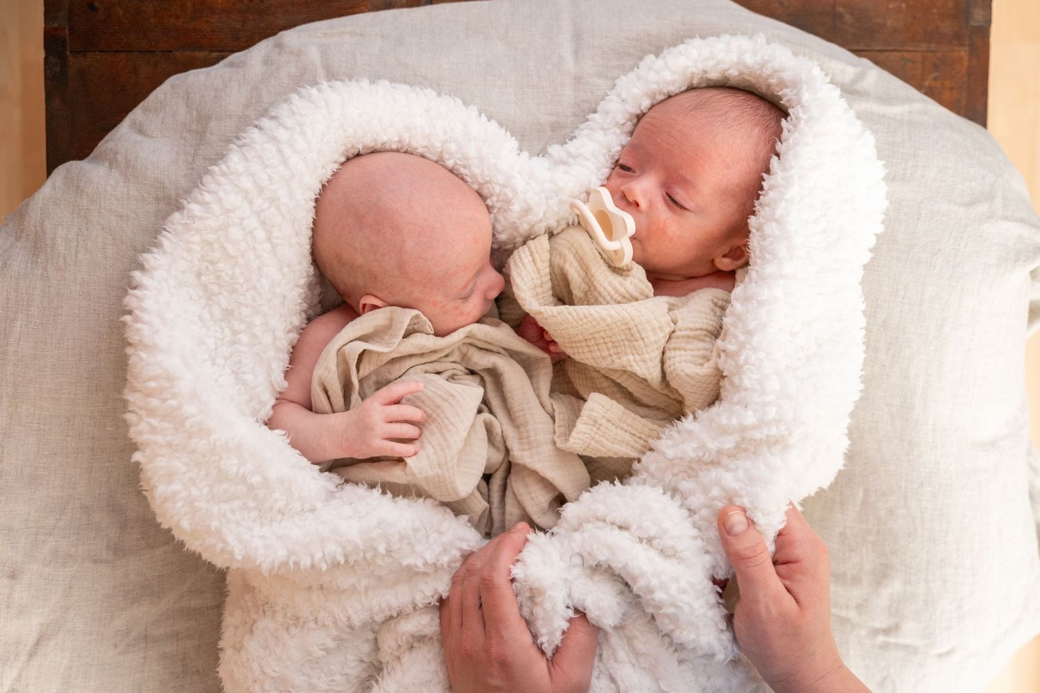 Newborn baby wrapped in soft white blankets during professional photography session. Whitney McLaren Photography