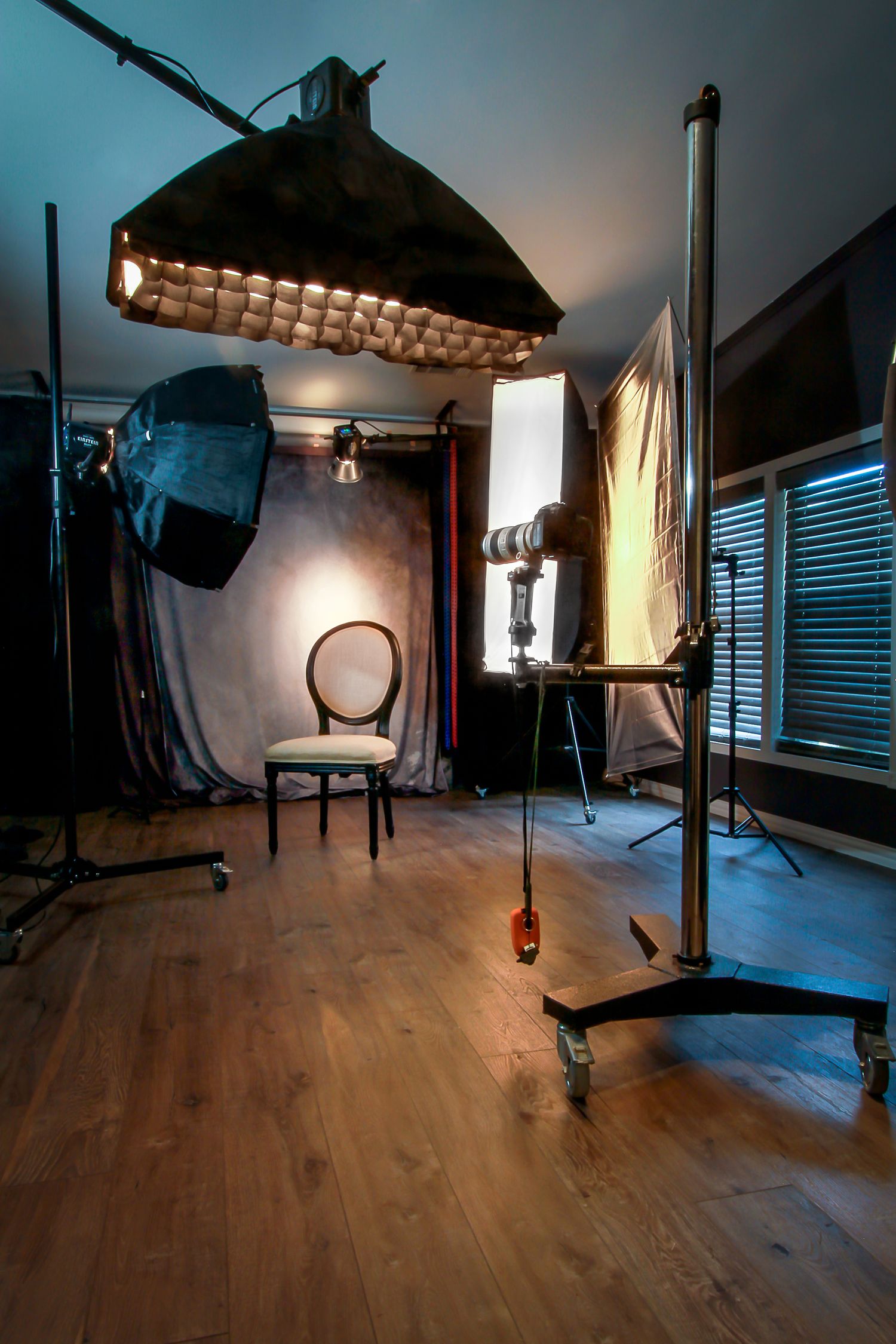 Professional High School Senior and Sports photography studio with lighting equipment, softboxes, and a lone chair against a backdrop.
