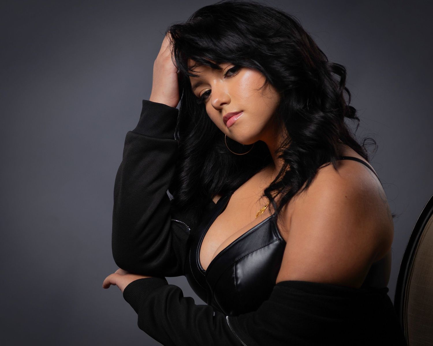 A woman in a black outfit poses dramatically against a dark background in a series of artistic portraits.