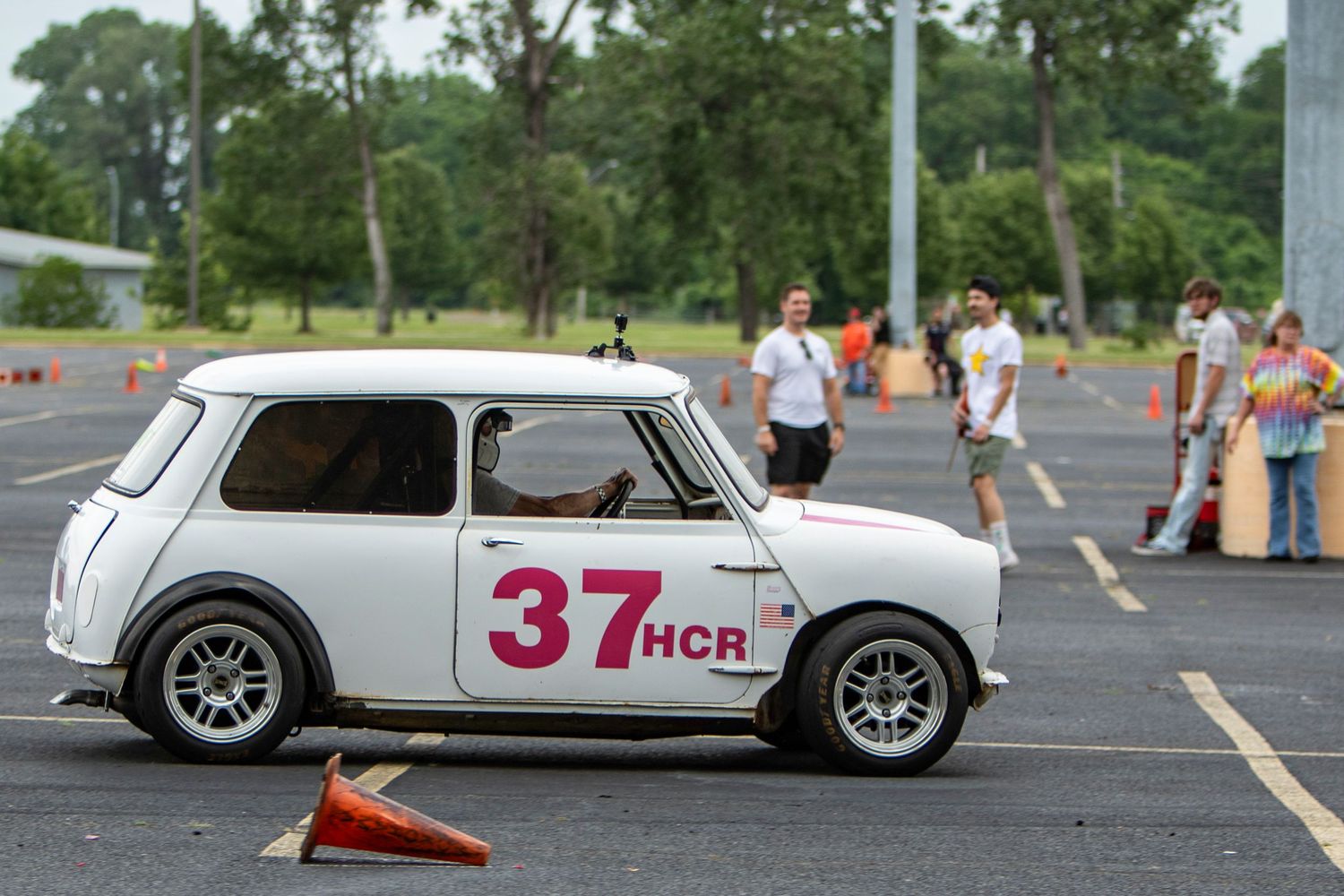 White Mini Cooper number 37 HCR racing in an autocross event on a parking lot course with orange cones.