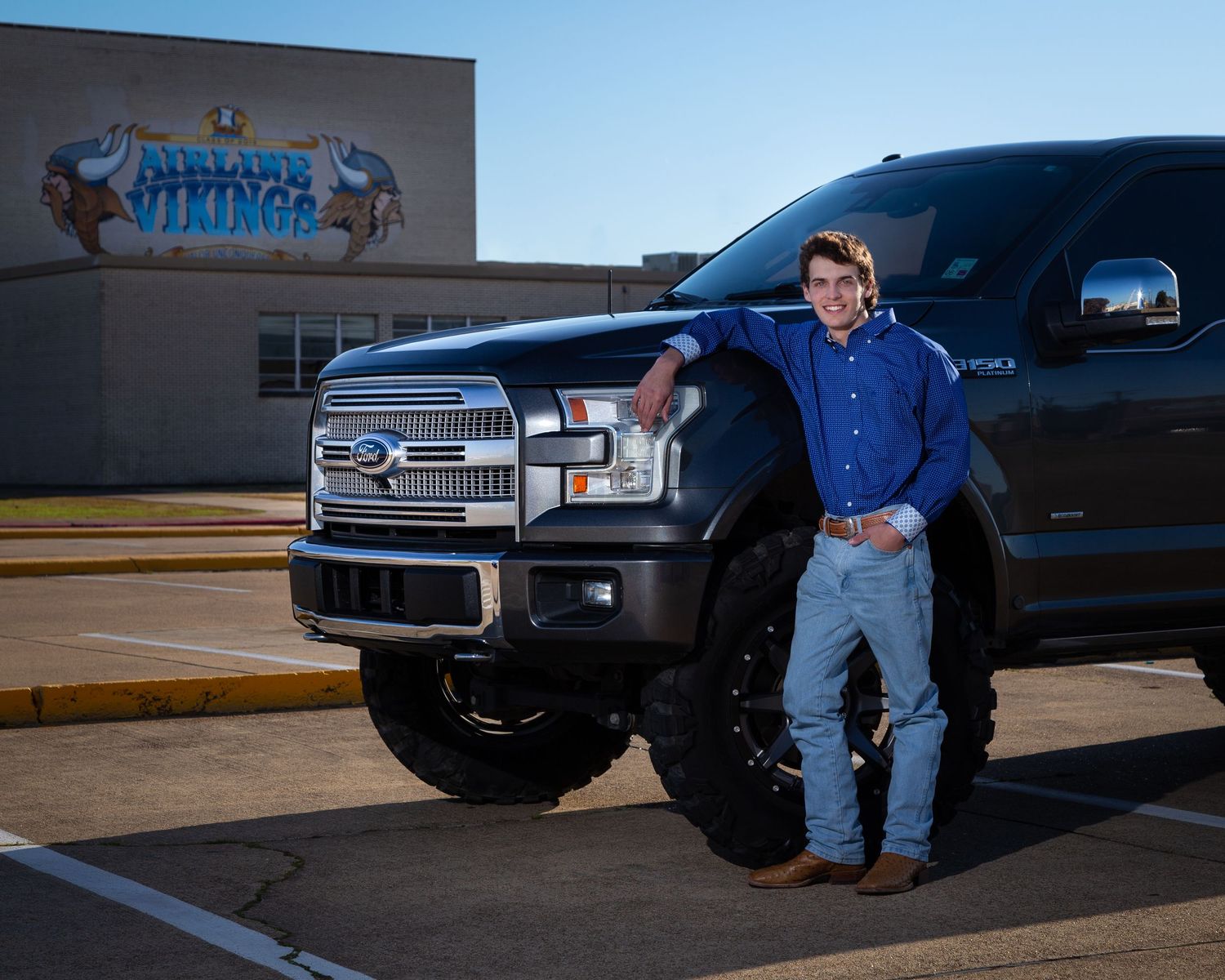 A lifted black Ford F150 truck parked in front of a building at dusk.