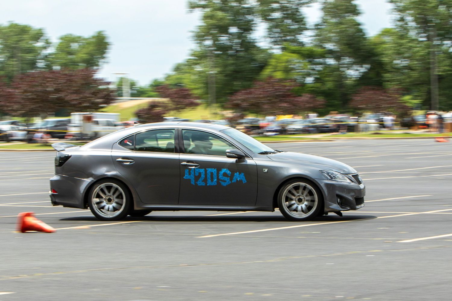 Gray Lexus sedan with racing number competing in an autocross event on a sunny day in a parking lot.
