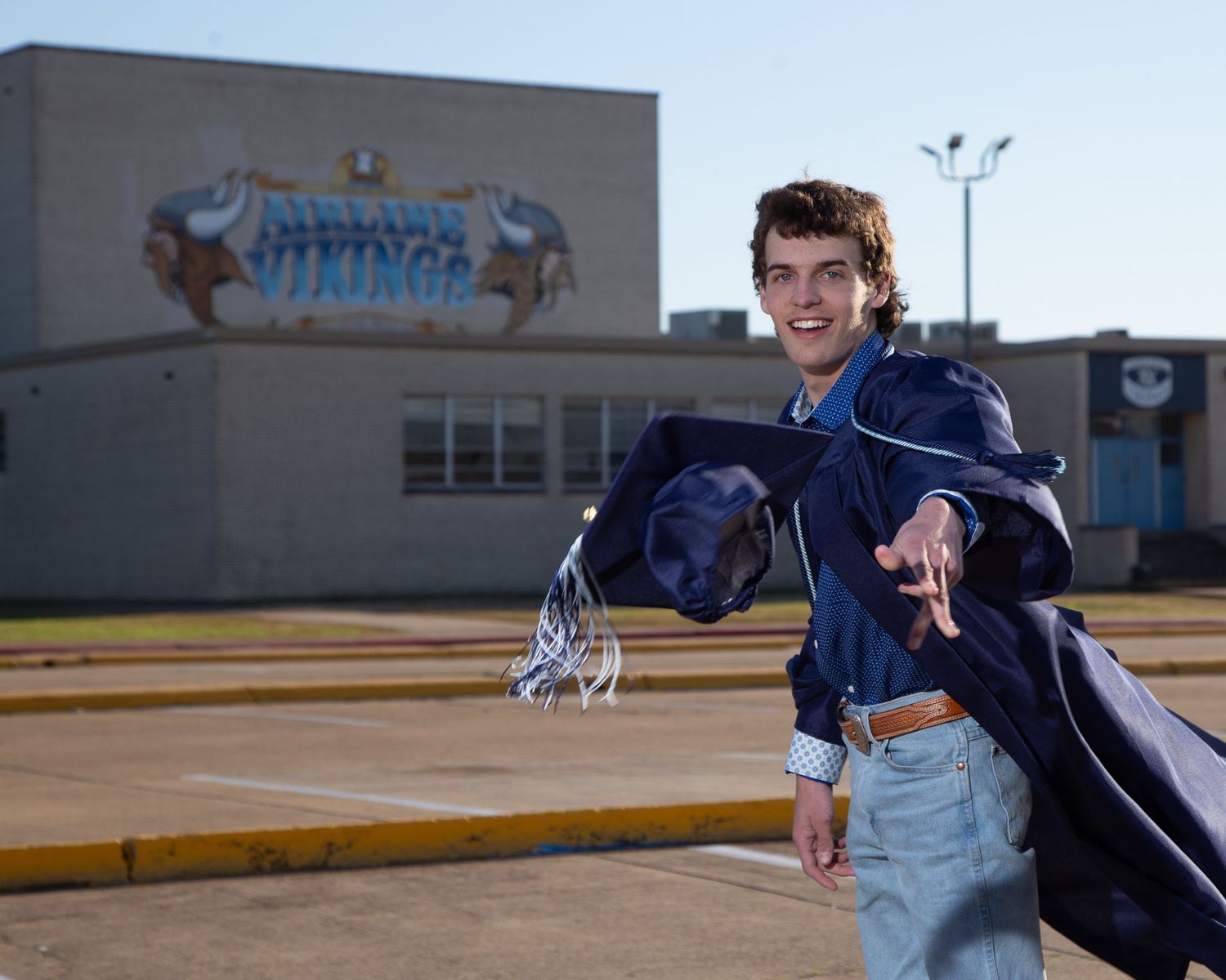 High school baseball player in navy uniform swings bat during practice session at outdoor field.