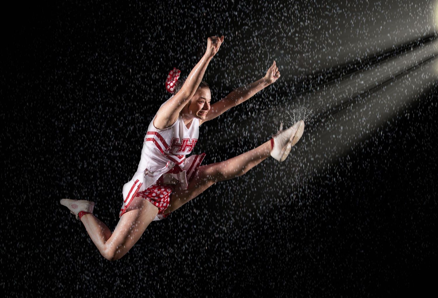 American football player diving to catch the ball during a night game under stadium lights.