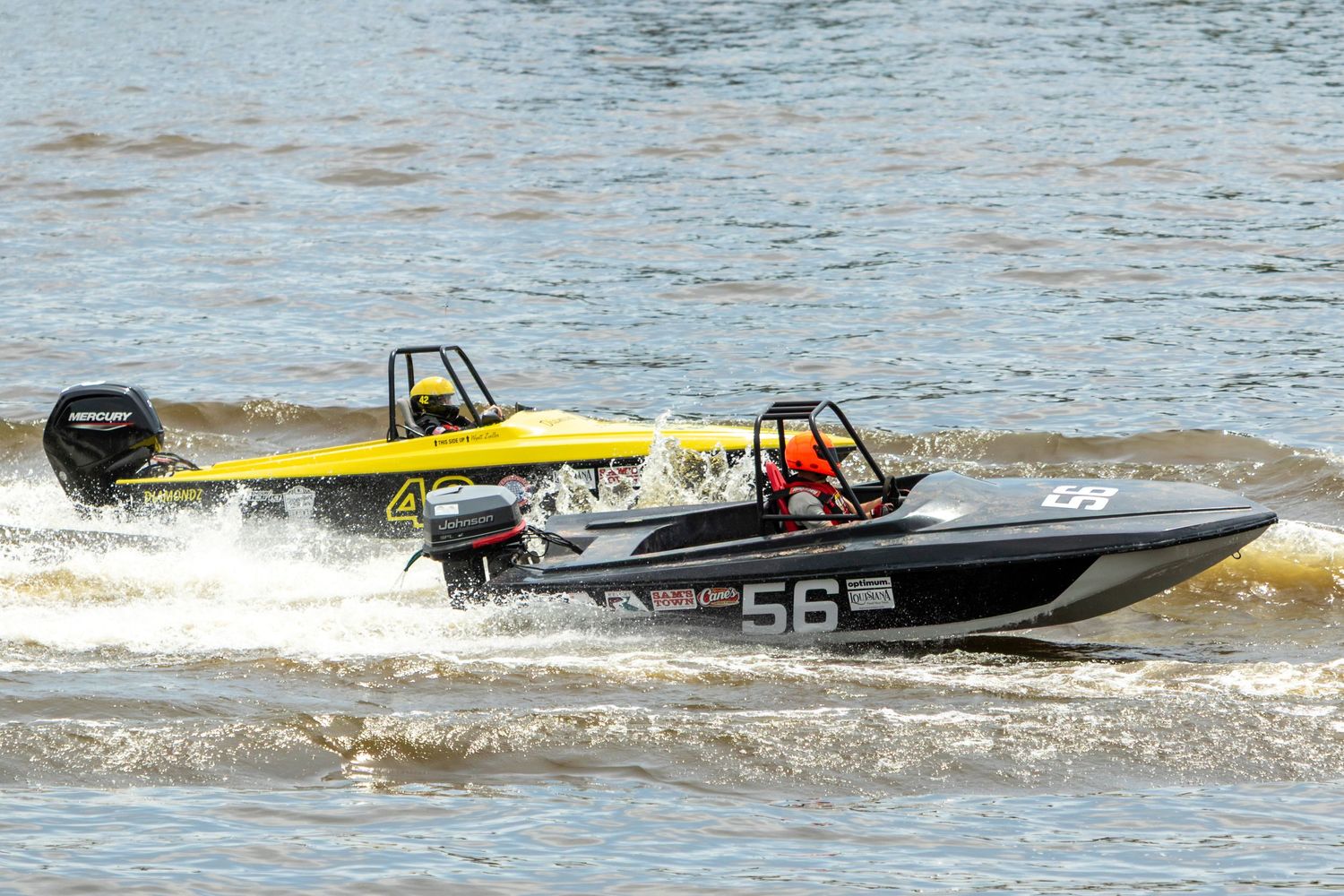 Two racing speedboats, numbered 56, competing on choppy brown water during a high-speed powerboat race.