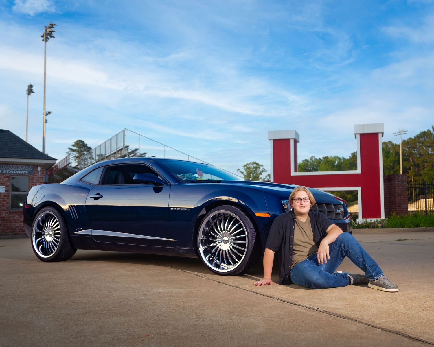 A blue custom car with large chrome wheels and lowered suspension shown from multiple angles in a parking lot.