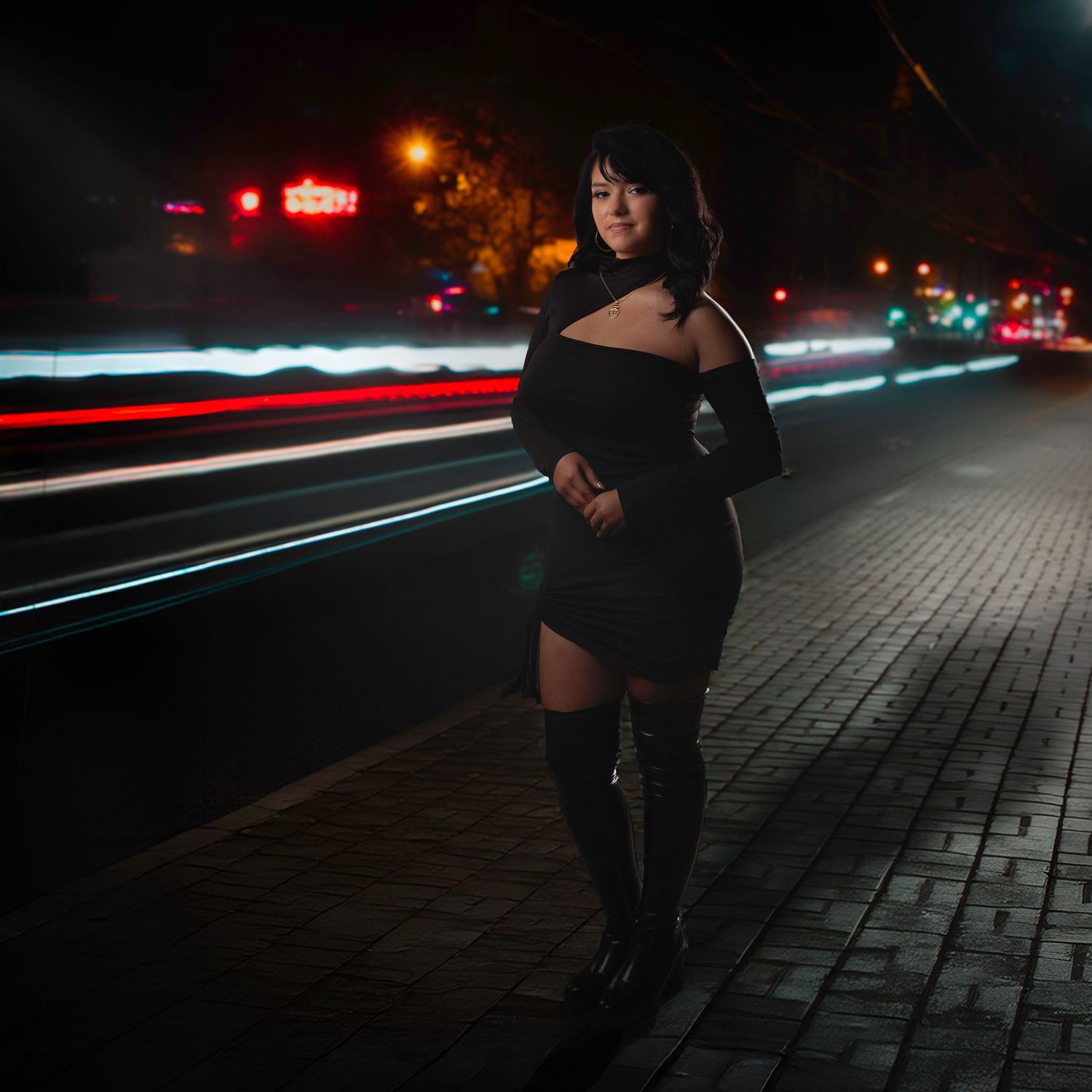 Long exposure night photography captures light trails and silhouette against urban backdrop.