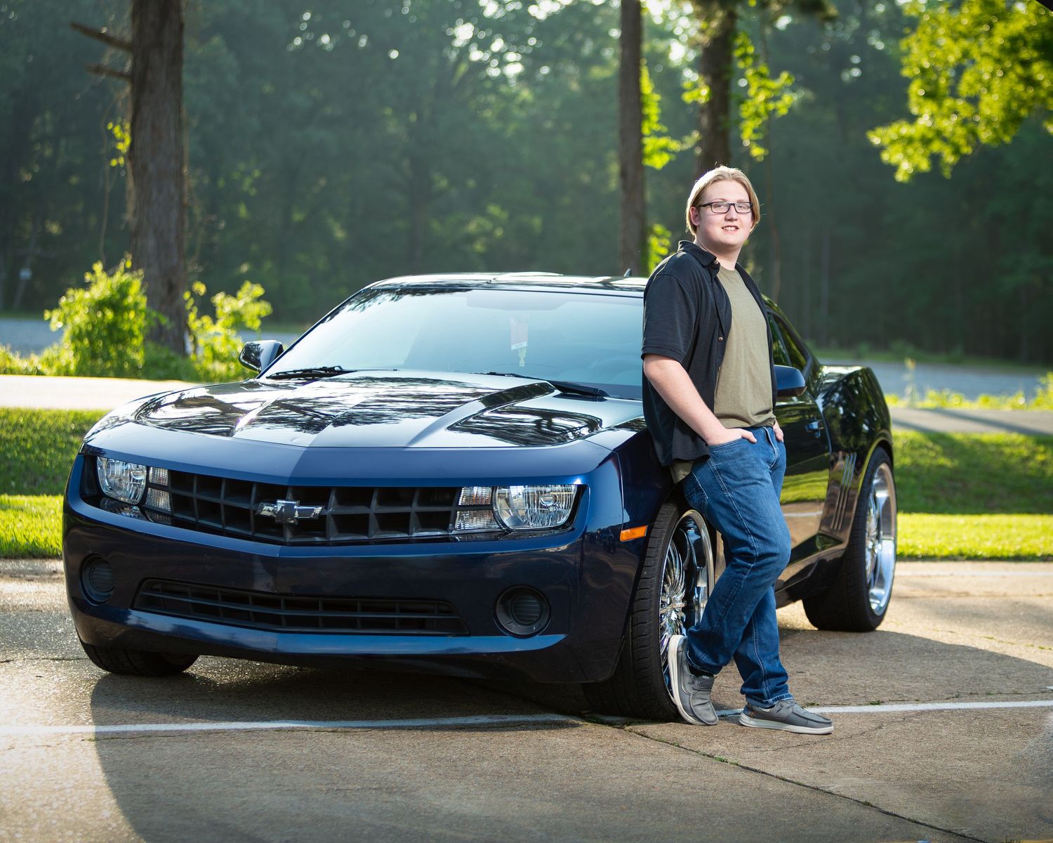 A blue Chevrolet Camaro parked in a scenic outdoor setting during golden hour lighting.