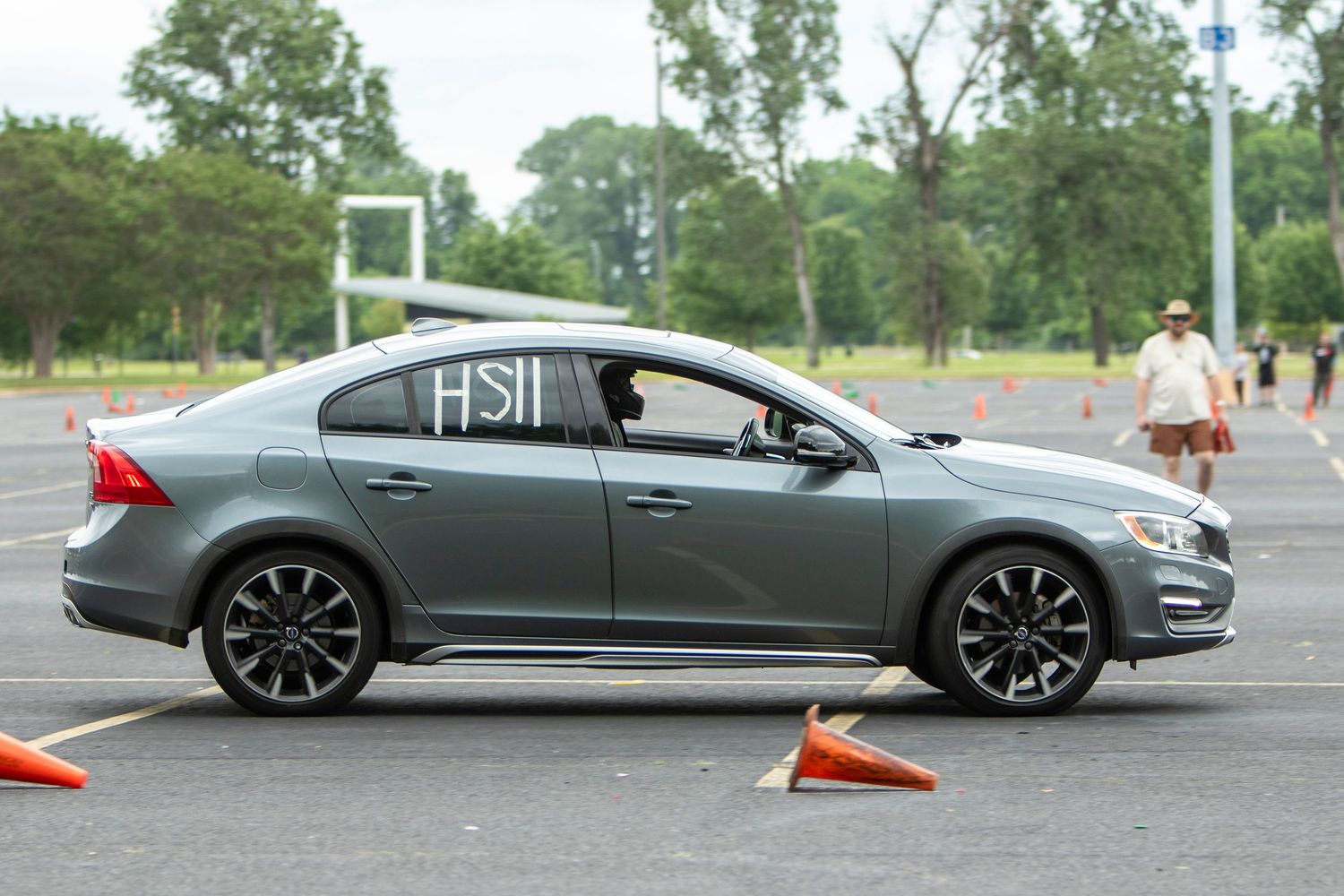 Gray Volvo S60 sedan navigating an autocross course marked with orange cones at an outdoor parking lot event.